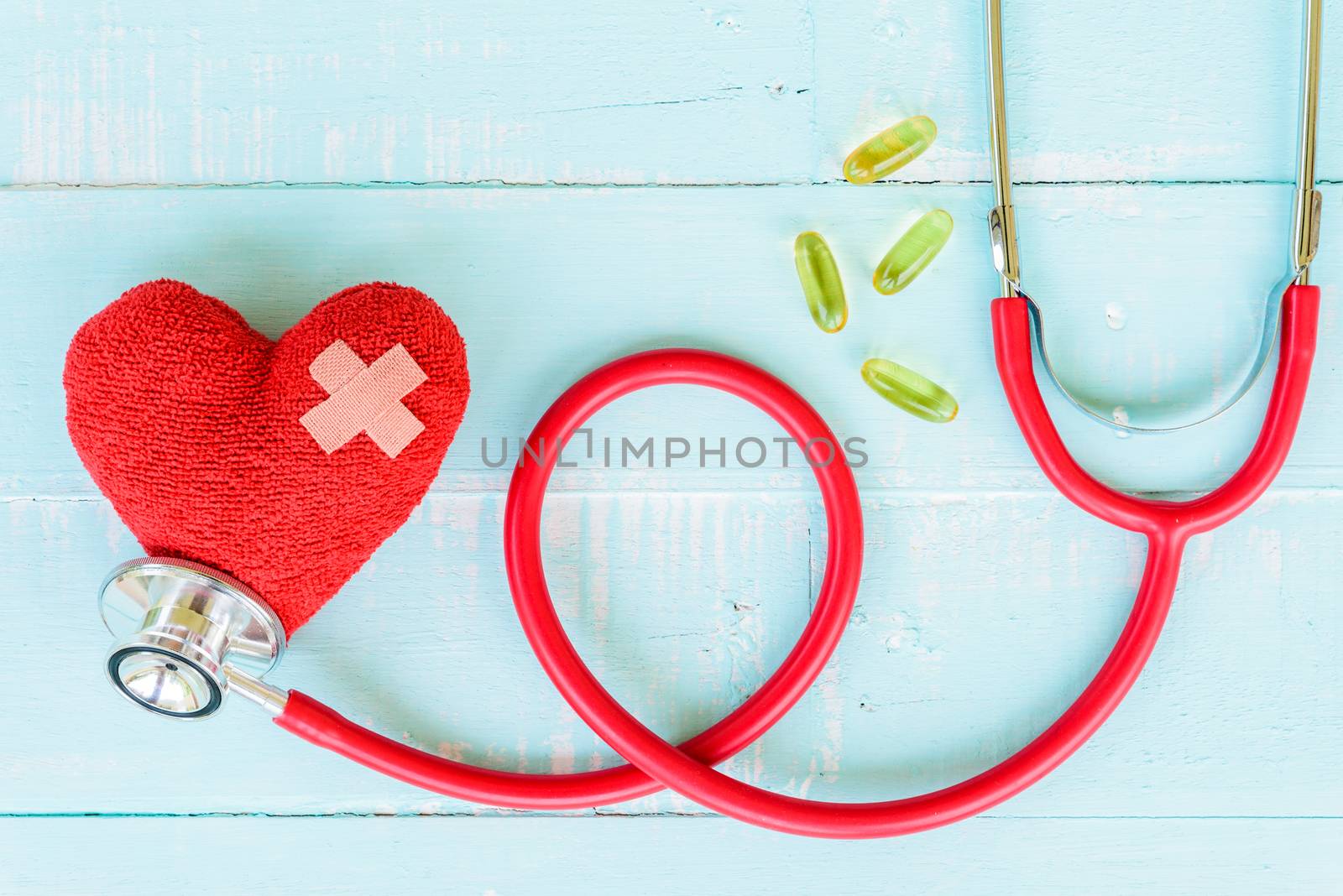 World health day, Healthcare and medical concept. Red heart with Stethoscope, thermometer and yellow Pill on Pastel white and blue wooden table background texture.