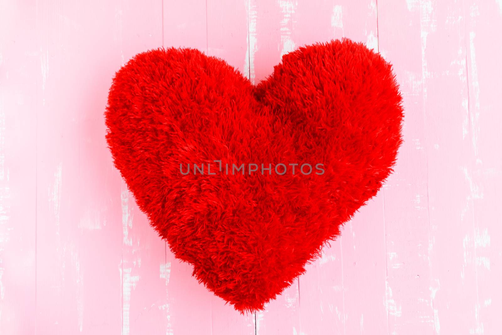 Beautiful big red pillow heart shape on white and pink wooden ba by spukkato