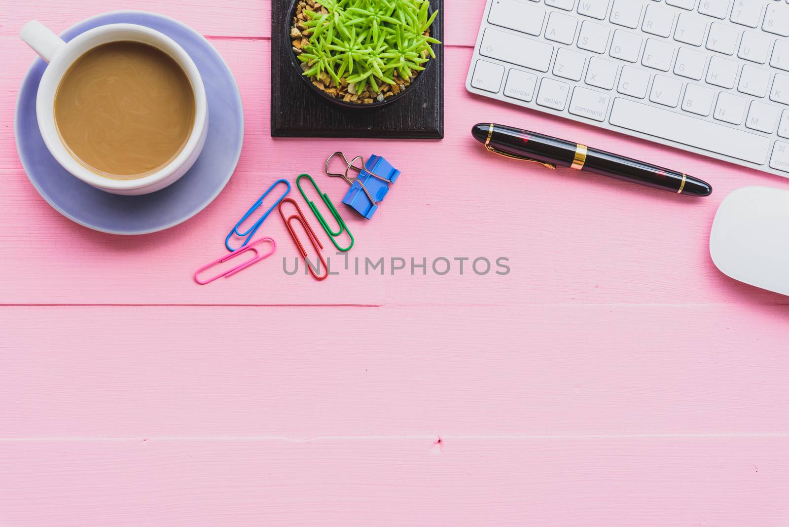 Top view office table with workspace and office accessories including calculator, mouse, keyboard, glasses, clips, flower, pen, pencil, note book, laptop and coffee on pink wooden background.