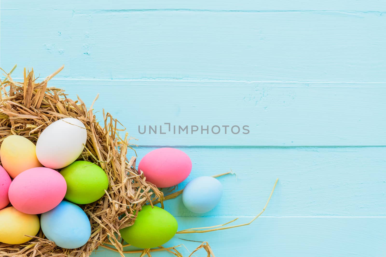 Colorful of Easter eggs in nest on pastel color bright blue and white wooden background.