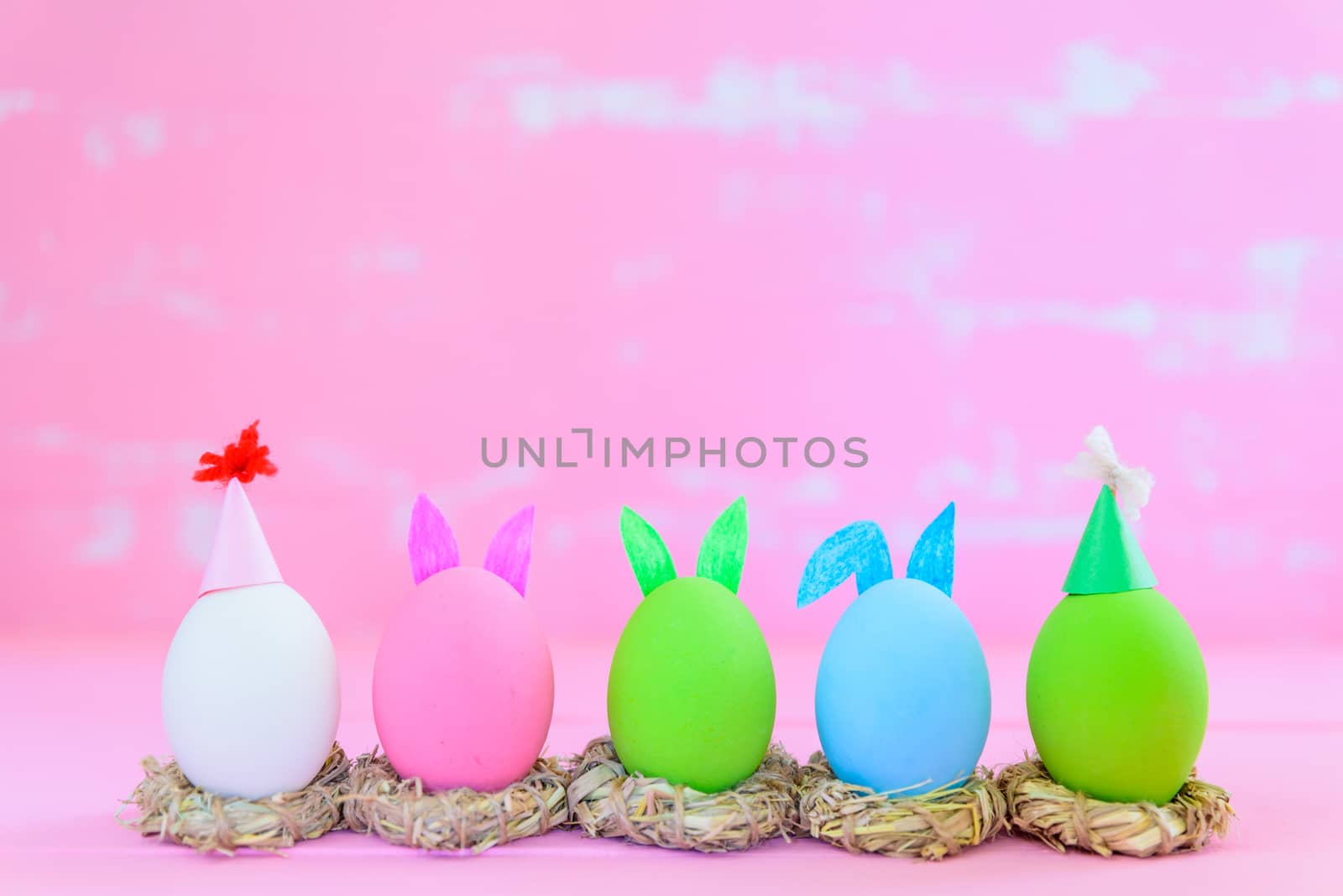 Soft focus of Row Easter eggs with colorful paper flowers on bright pink and white wooden background.