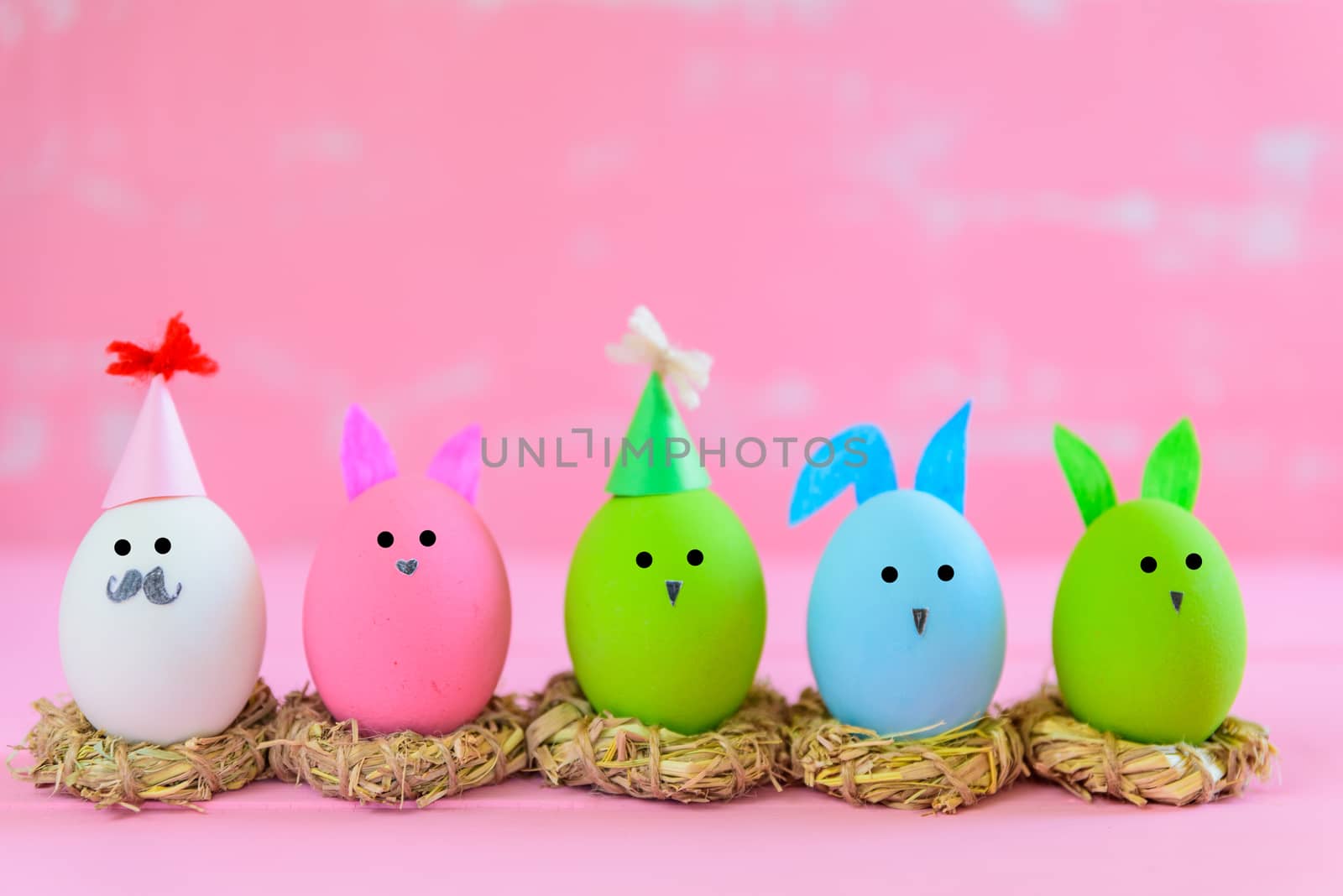 Row Easter eggs with colorful paper flowers on bright pink and white wooden background.