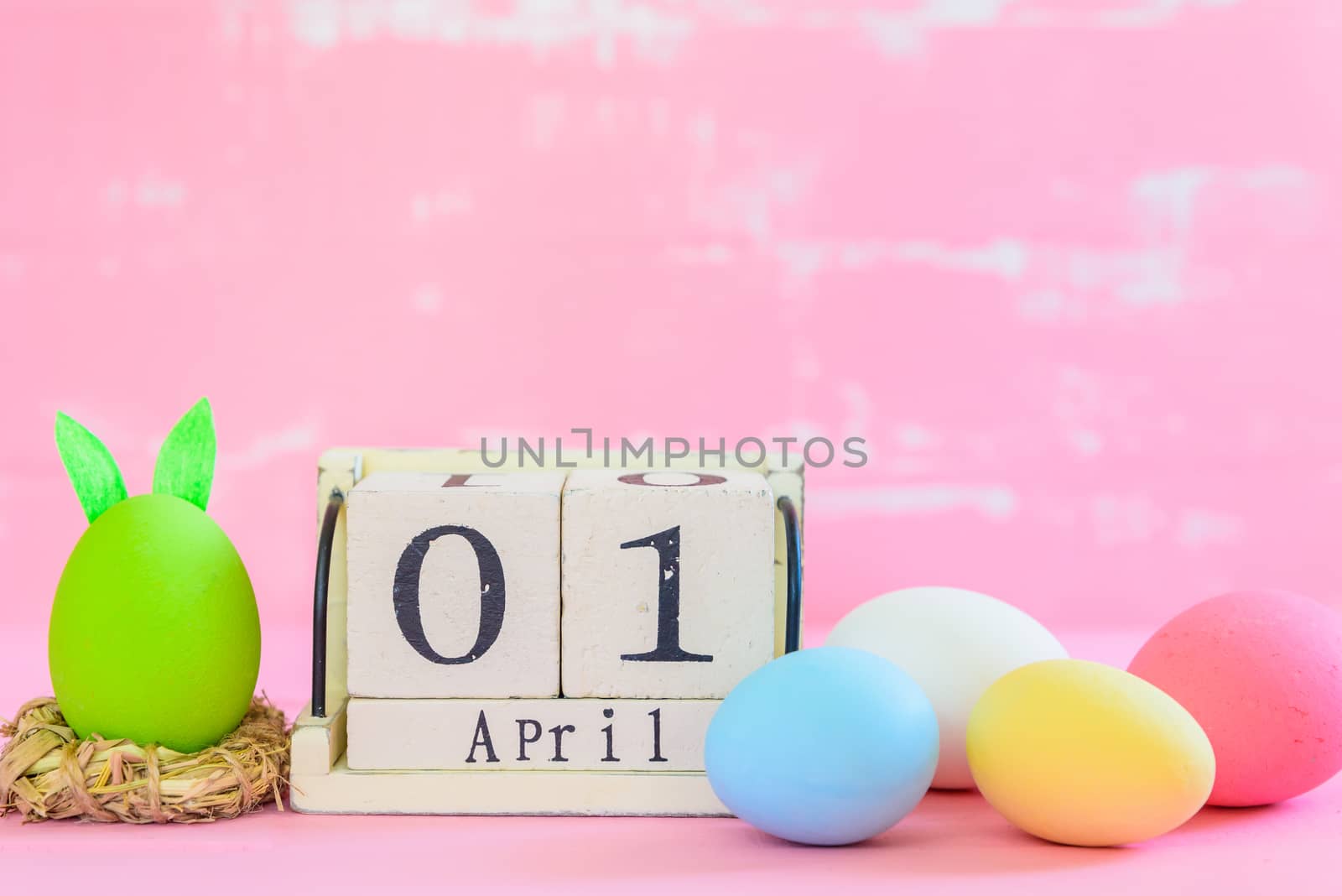 Row Easter eggs with colorful paper flowers on bright pink and white wooden background.