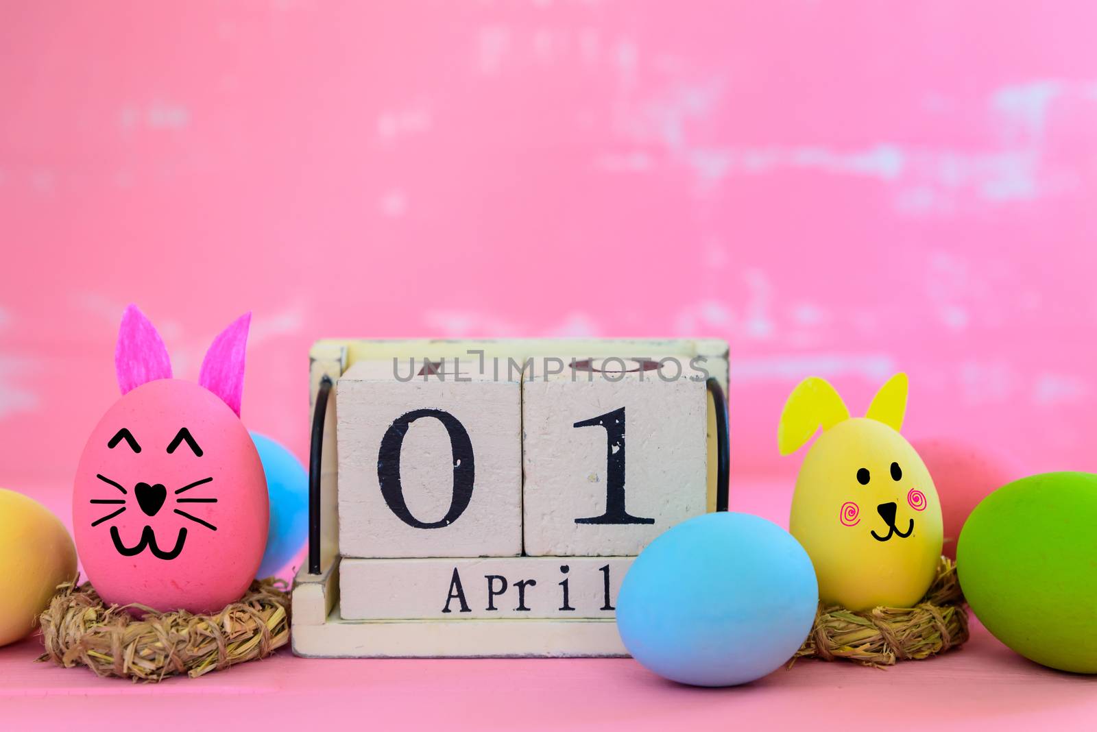 Wooden block calendar for Easter Day, April 1. Colorful of Easter eggs in nest on pastel color bright blue and white wooden background.