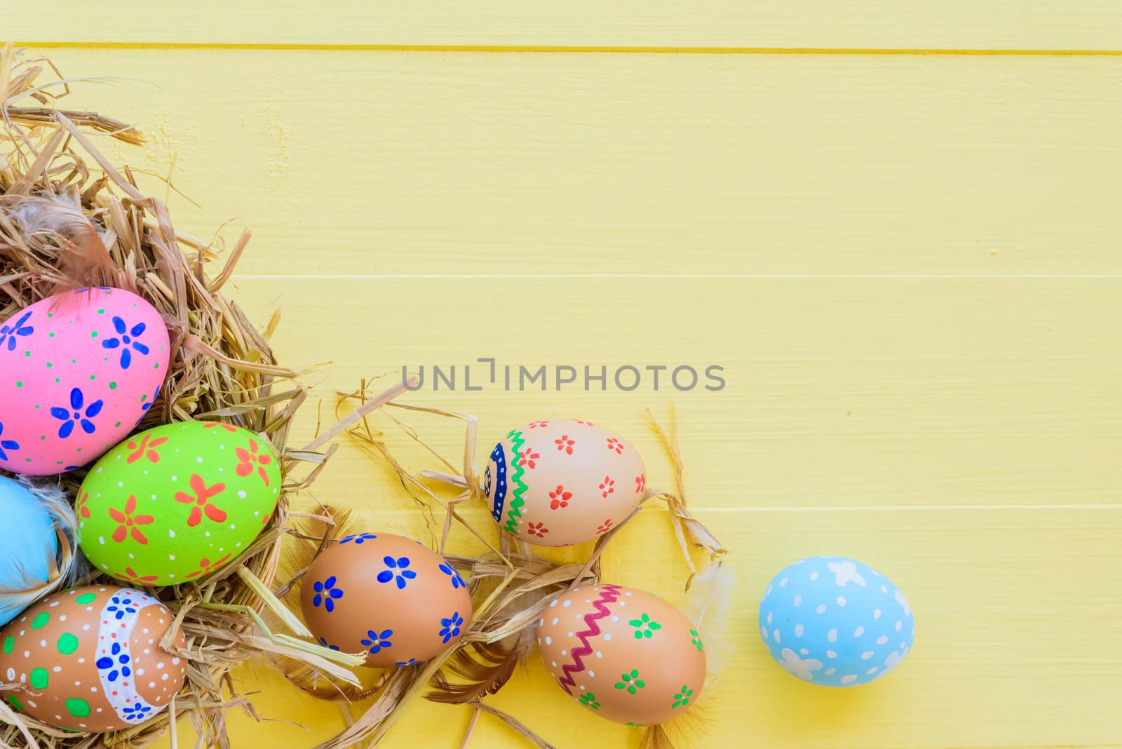 Happy easter! Colorful of Easter eggs in nest on pastel color bright yellow and white wooden background.