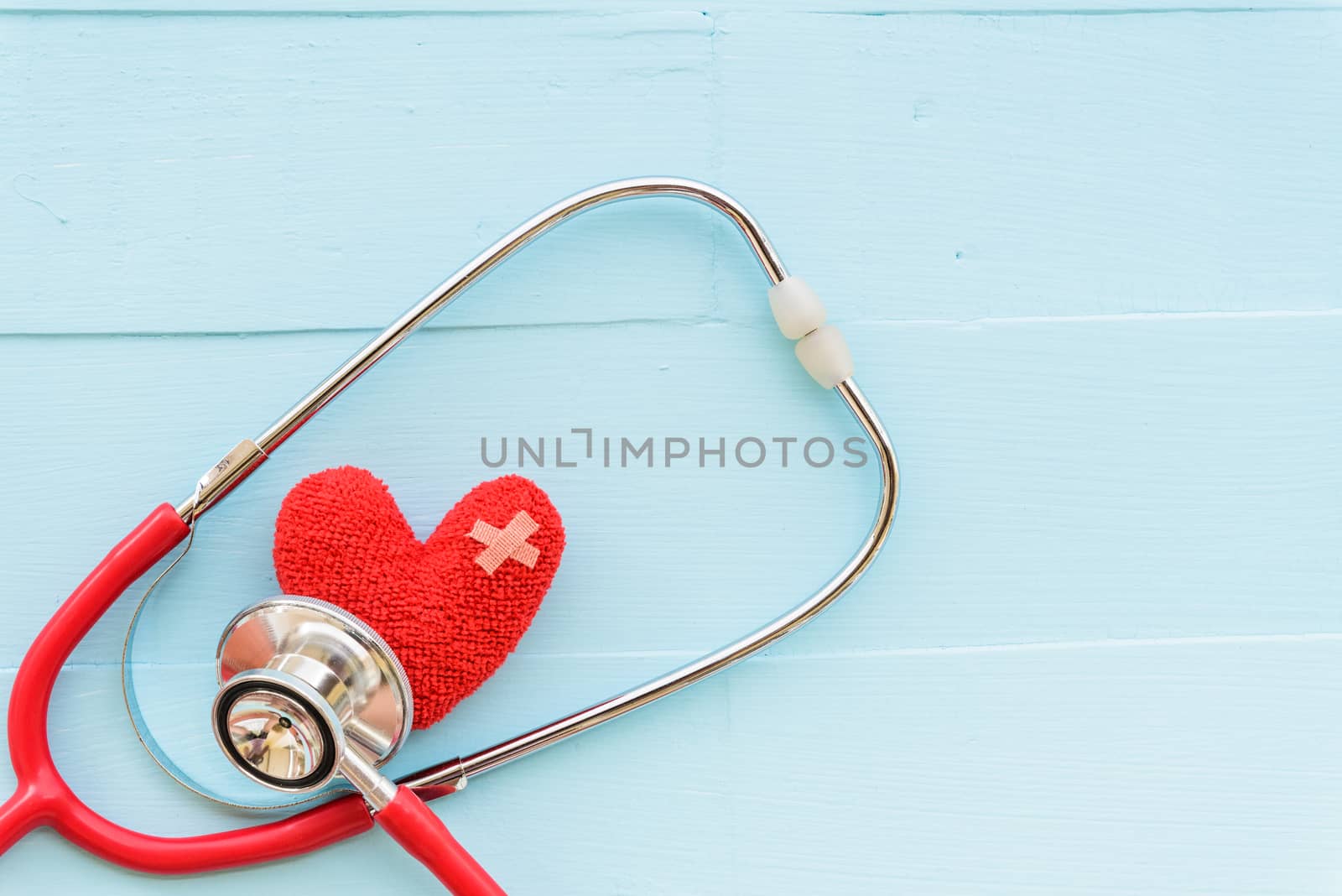 World health day, Healthcare and medical concept. Woman hand holding red heart with Stethoscope, notepad or notebook, thermometer and yellow Pill on Pastel white and blue wooden table background texture.