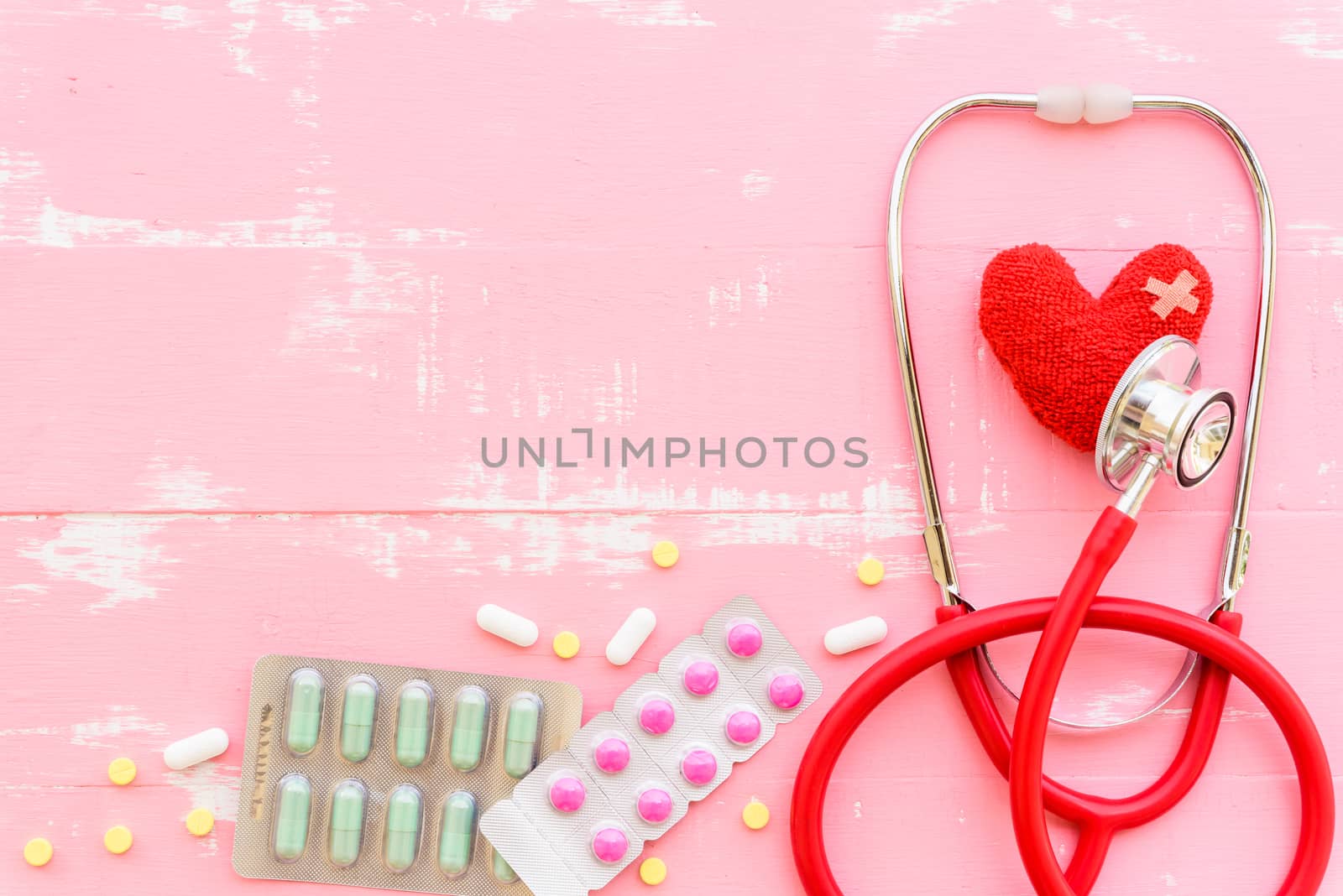 World health day, Healthcare and medical concept. Woman hand holding red heart with Stethoscope, notepad or notebook, thermometer and yellow Pill on Pastel white and blue wooden table background texture.