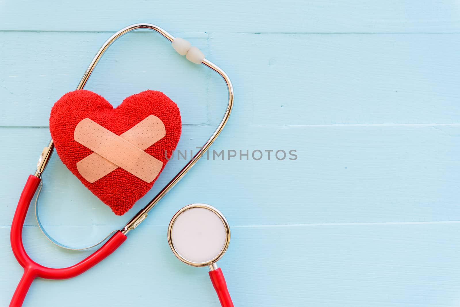 World health day, Healthcare and medical concept. Woman hand holding red heart with Stethoscope, notepad or notebook, thermometer and yellow Pill on Pastel white and blue wooden table background texture.