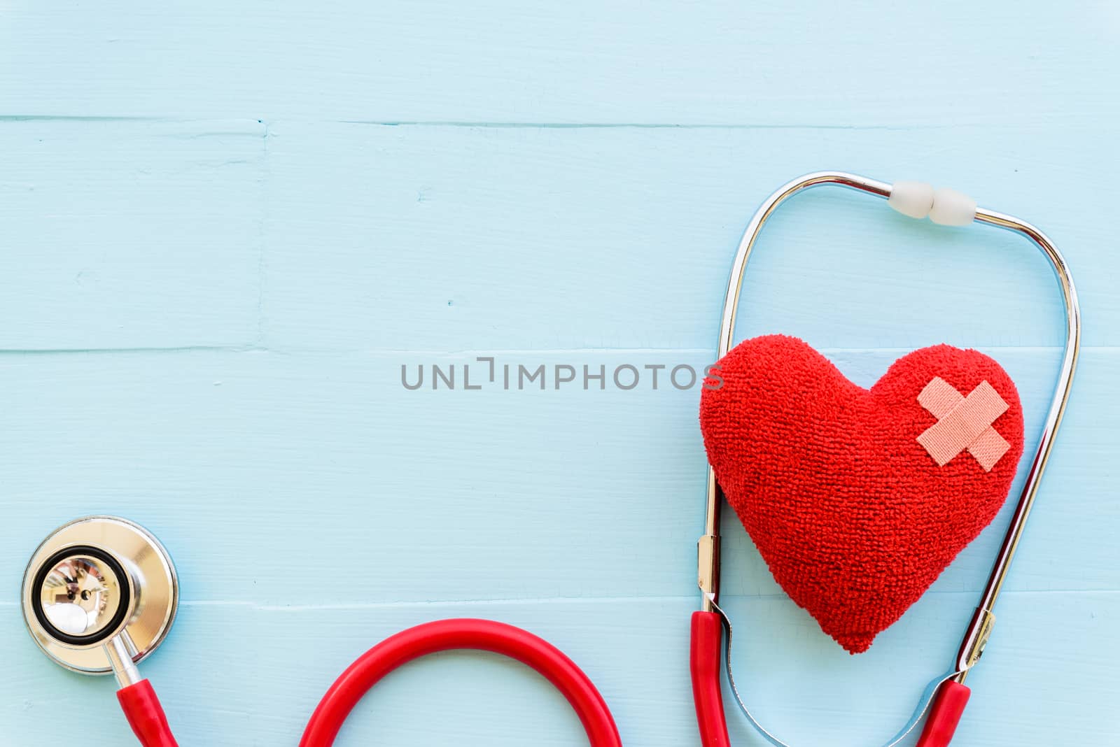 World health day, Healthcare and medical concept. Woman hand holding red heart with Stethoscope, notepad or notebook, thermometer and yellow Pill on Pastel white and blue wooden table background texture.
