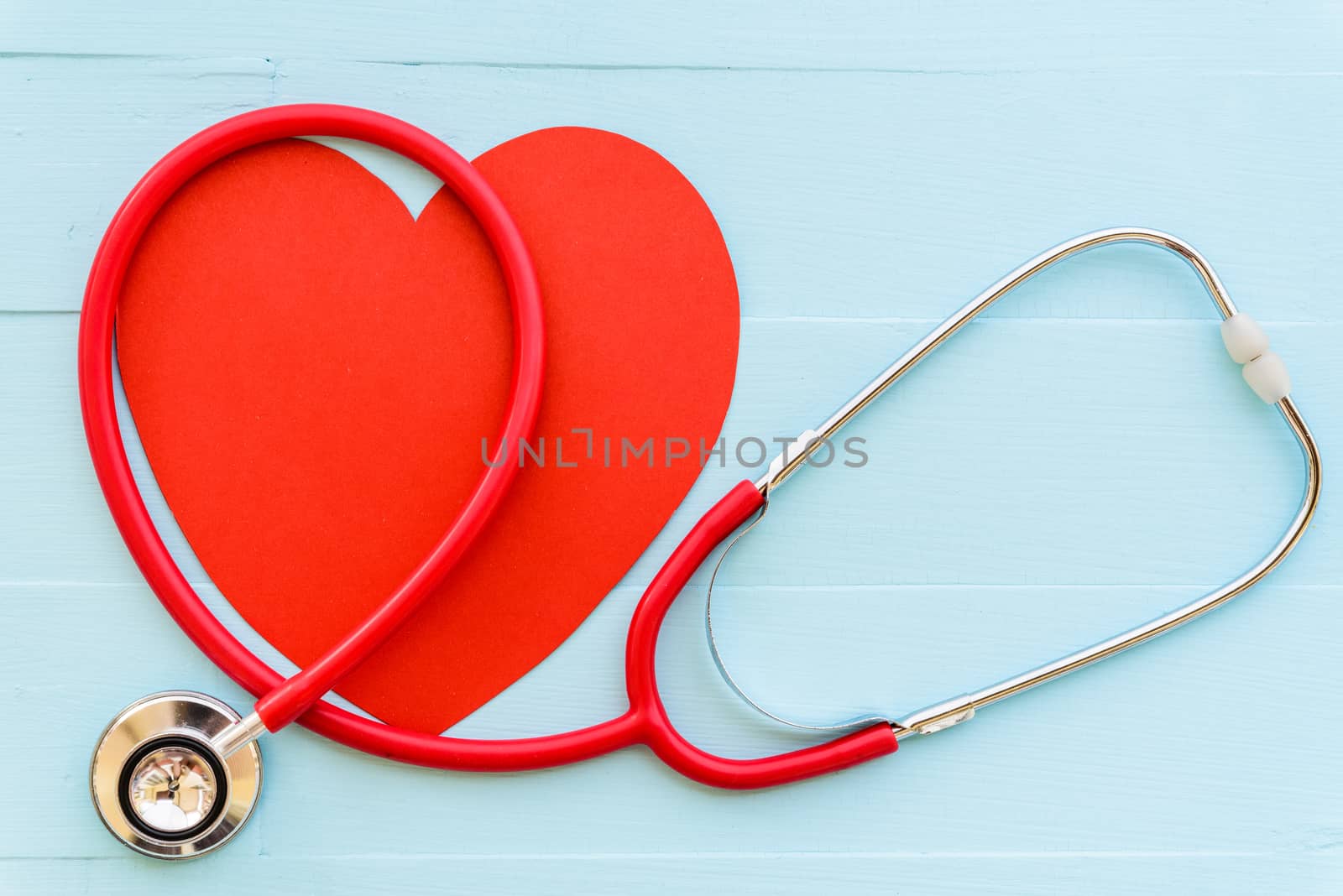 World health day, Healthcare and medical concept. Woman hand holding red heart with Stethoscope, notepad or notebook, thermometer and yellow Pill on Pastel white and blue wooden table background texture.