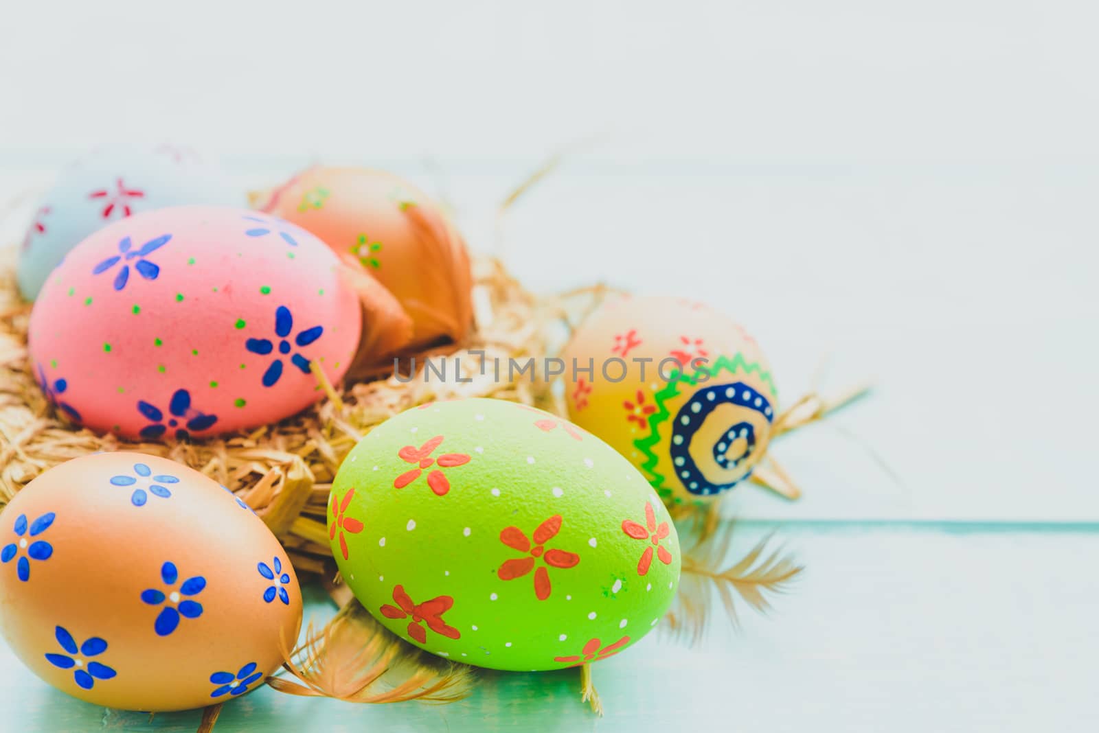 Happy easter! Colorful of Easter eggs in nest on pastel color bright green and white wooden background.