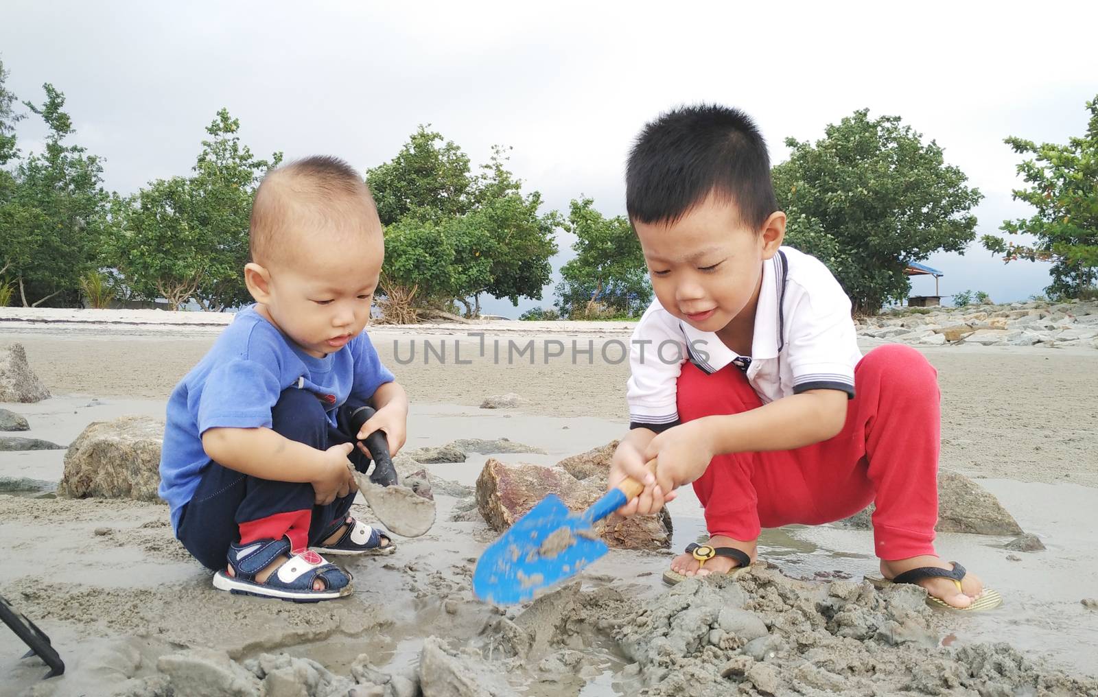 Asian children playing sand at beach.