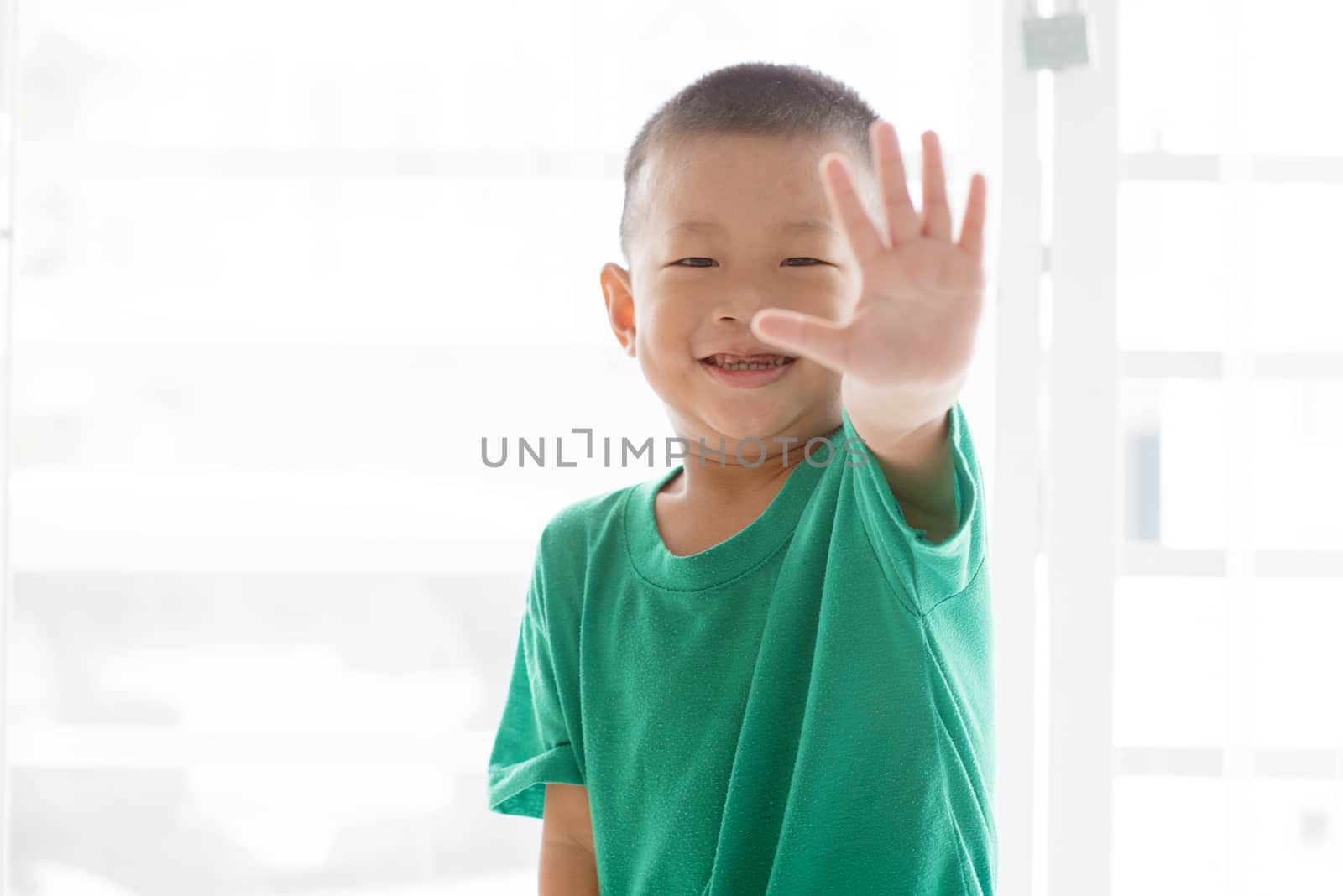 Young child at home. Playful Asian boy showing palm and giving high five.