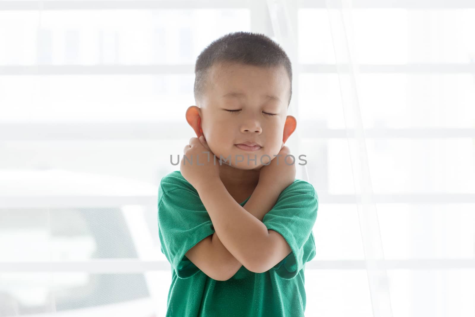 Young child at home. Playful Asian boy get punished by pulling ears.