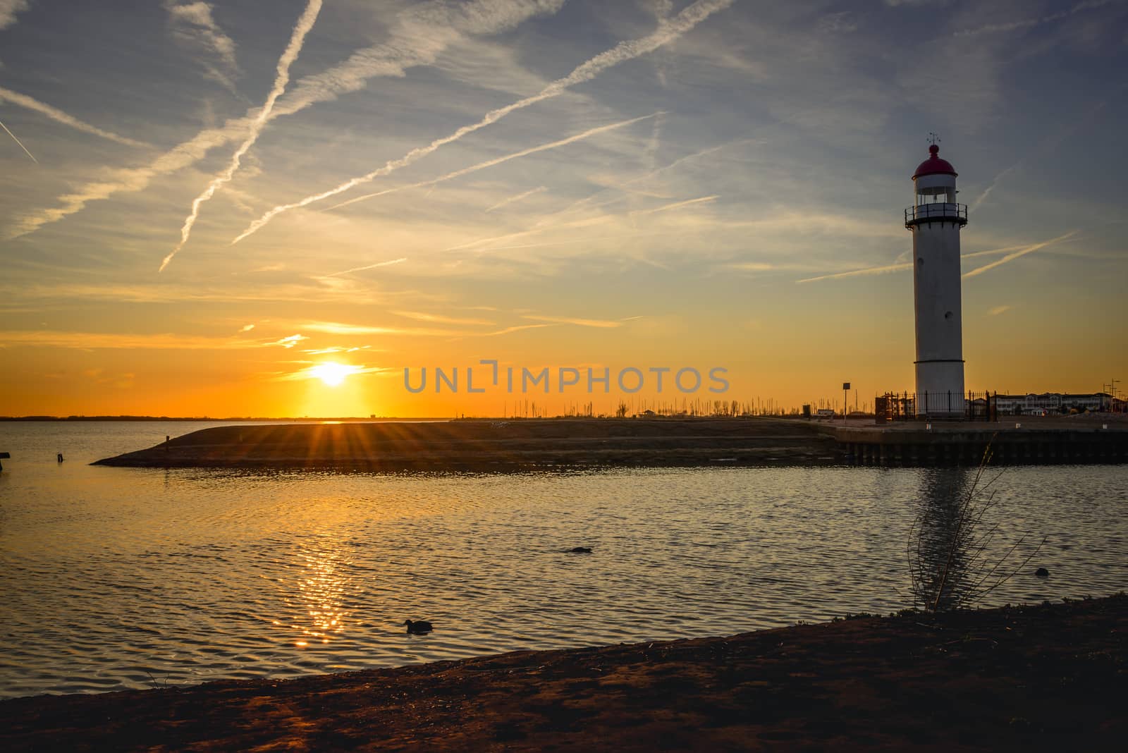 the lighthouse of hellevoetsluis in the sunset on the haringvliet, with red sunlight over the harbour