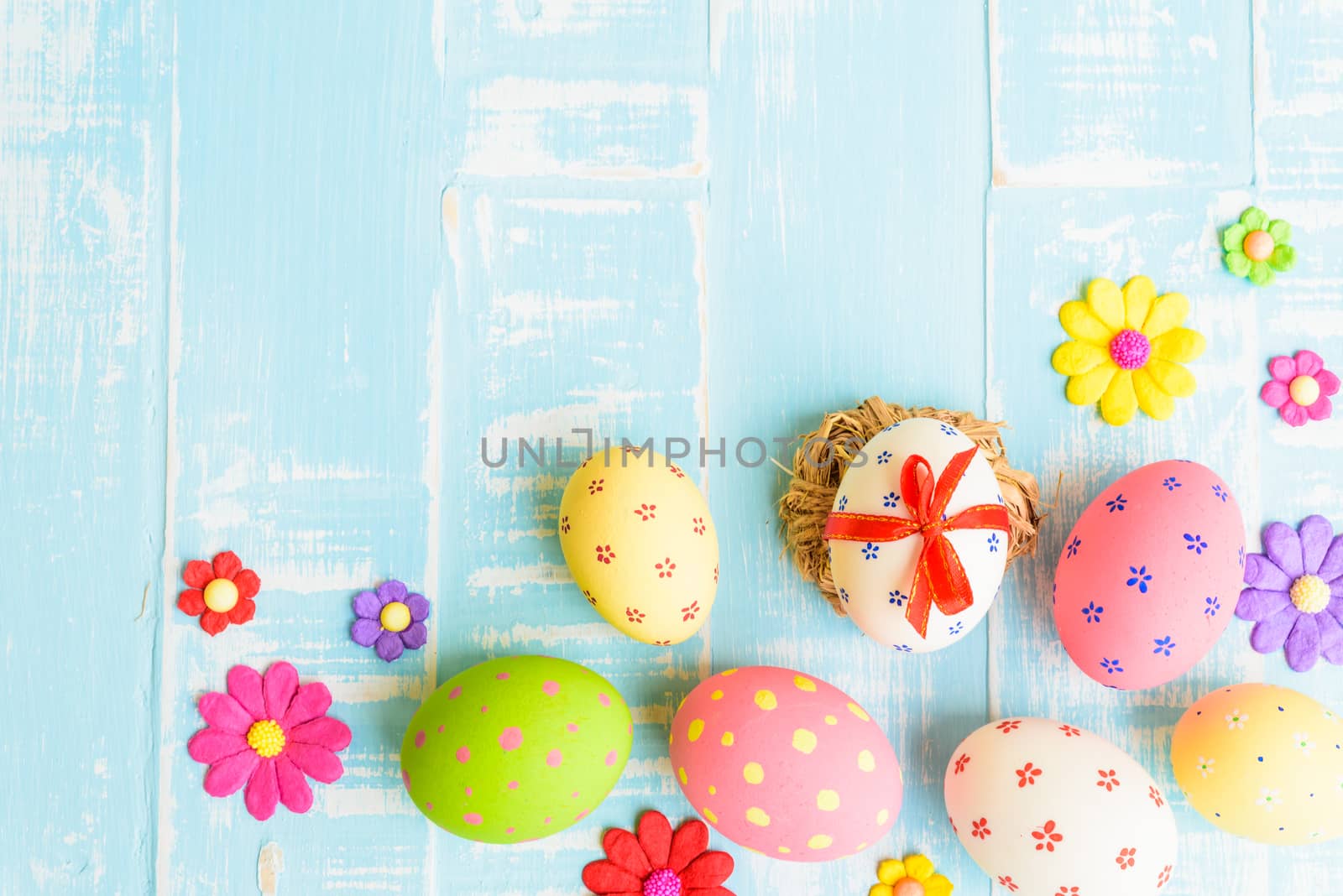 Happy easter! Colorful of Easter eggs in nest on pastel color bright green and white wooden background.