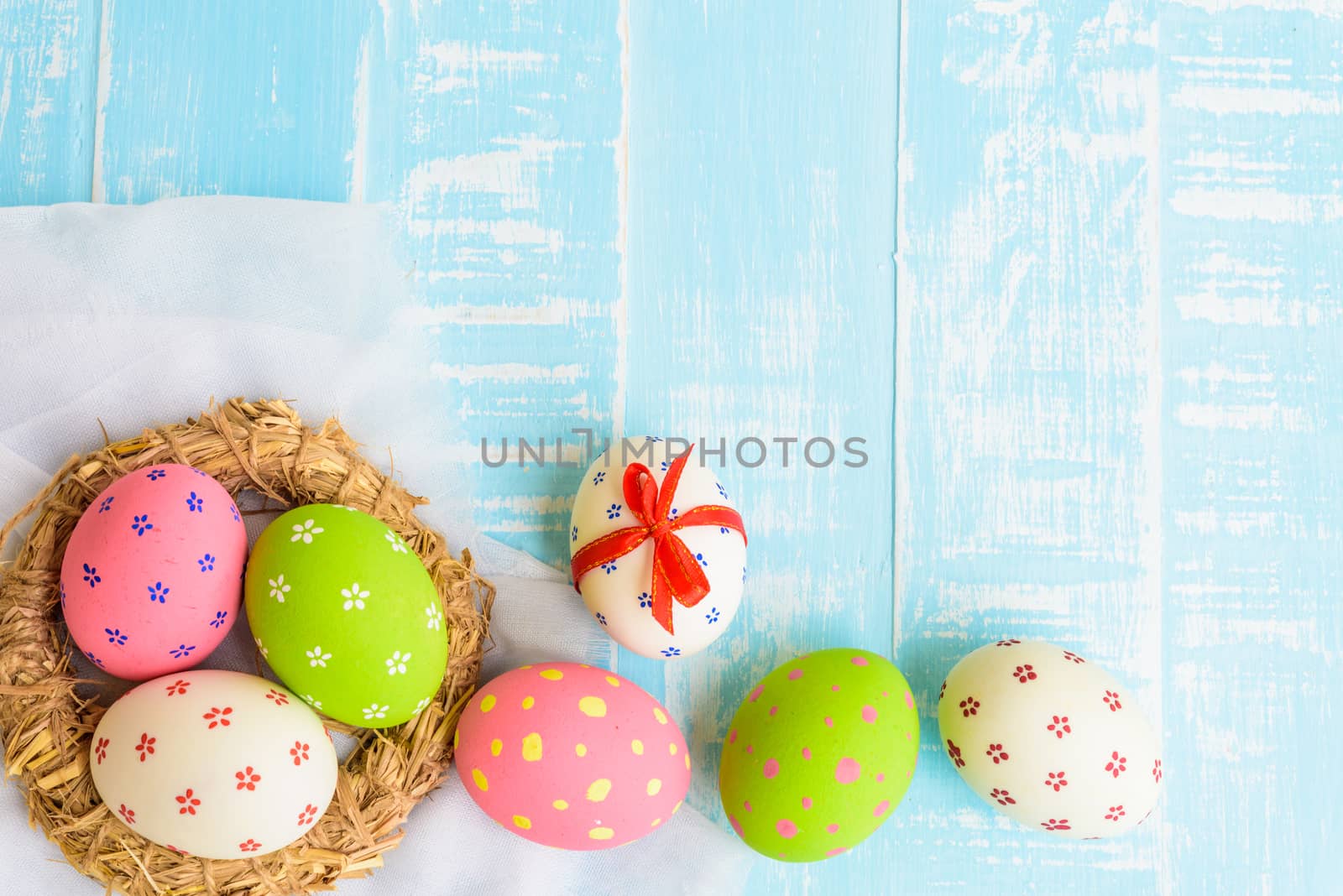 Happy easter! Colorful of Easter eggs in nest on pastel color bright green and white wooden background.