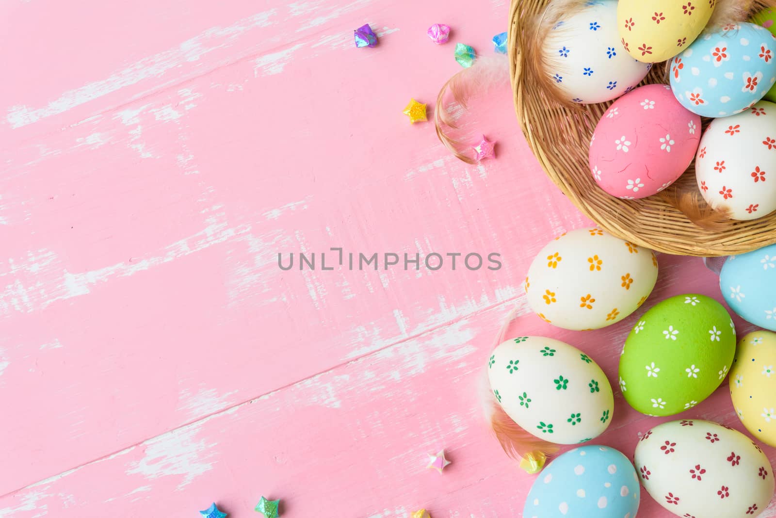 Happy easter! Colorful of Easter eggs in nest with paper star, flower and Feather on pastel color bright pink and white wooden background.