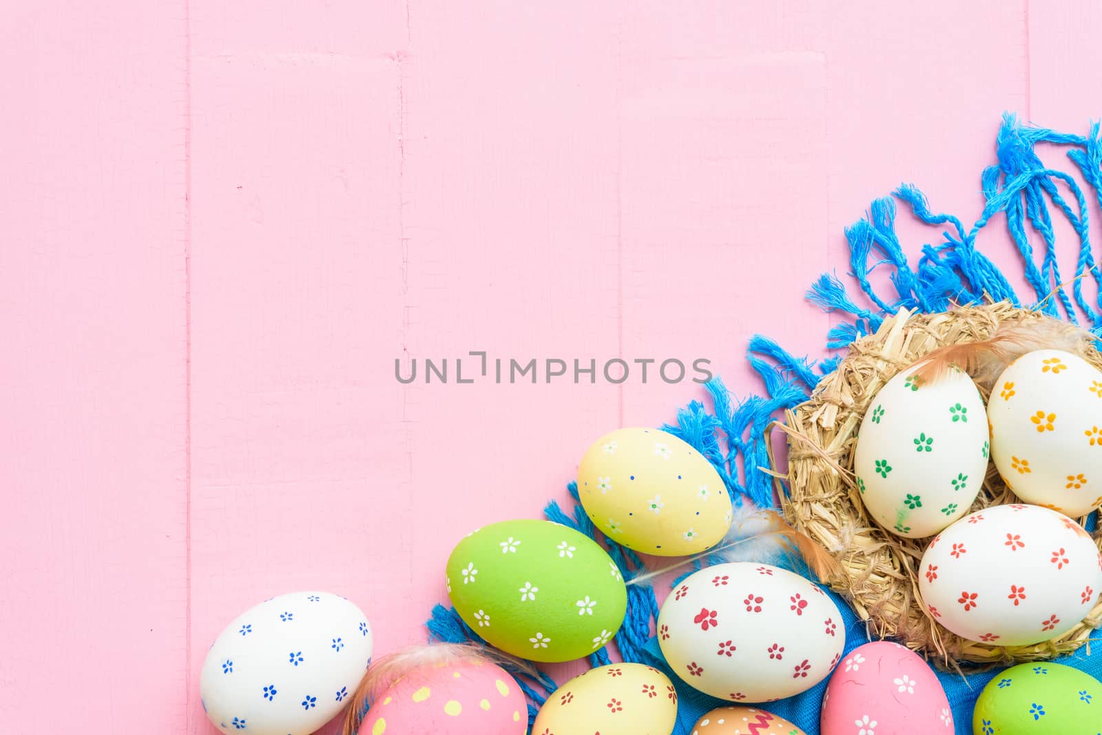 Happy easter! Colorful of Easter eggs in nest with paper star, flower and Feather on pastel color bright pink and white wooden background.