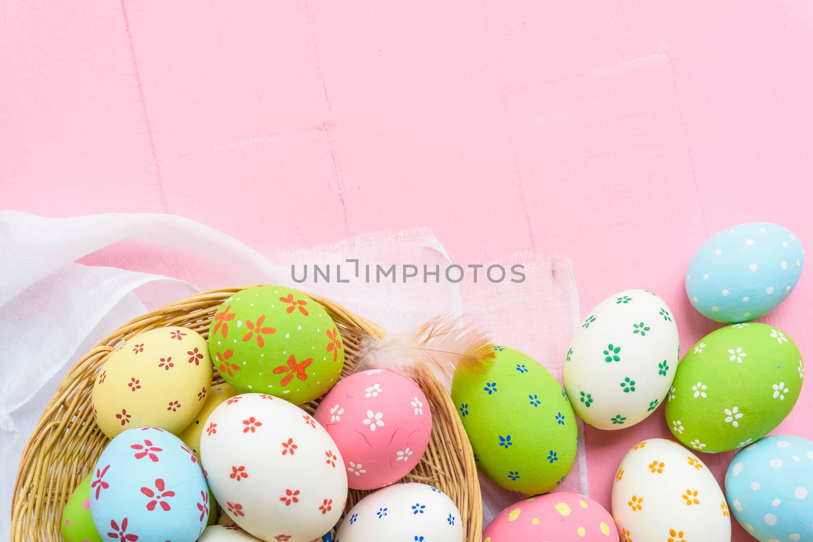 Happy easter! Colorful of Easter eggs in nest with paper star, flower and Feather on pastel color bright pink and white wooden background.