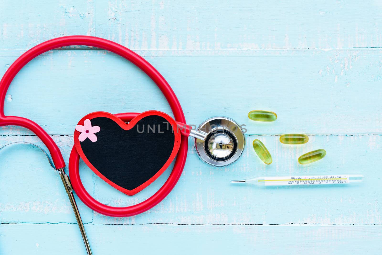 World health day, Healthcare and medical concept. Stethoscope, red and black heart, thermometer and yellow Pill on Pastel white and blue wooden table background texture.