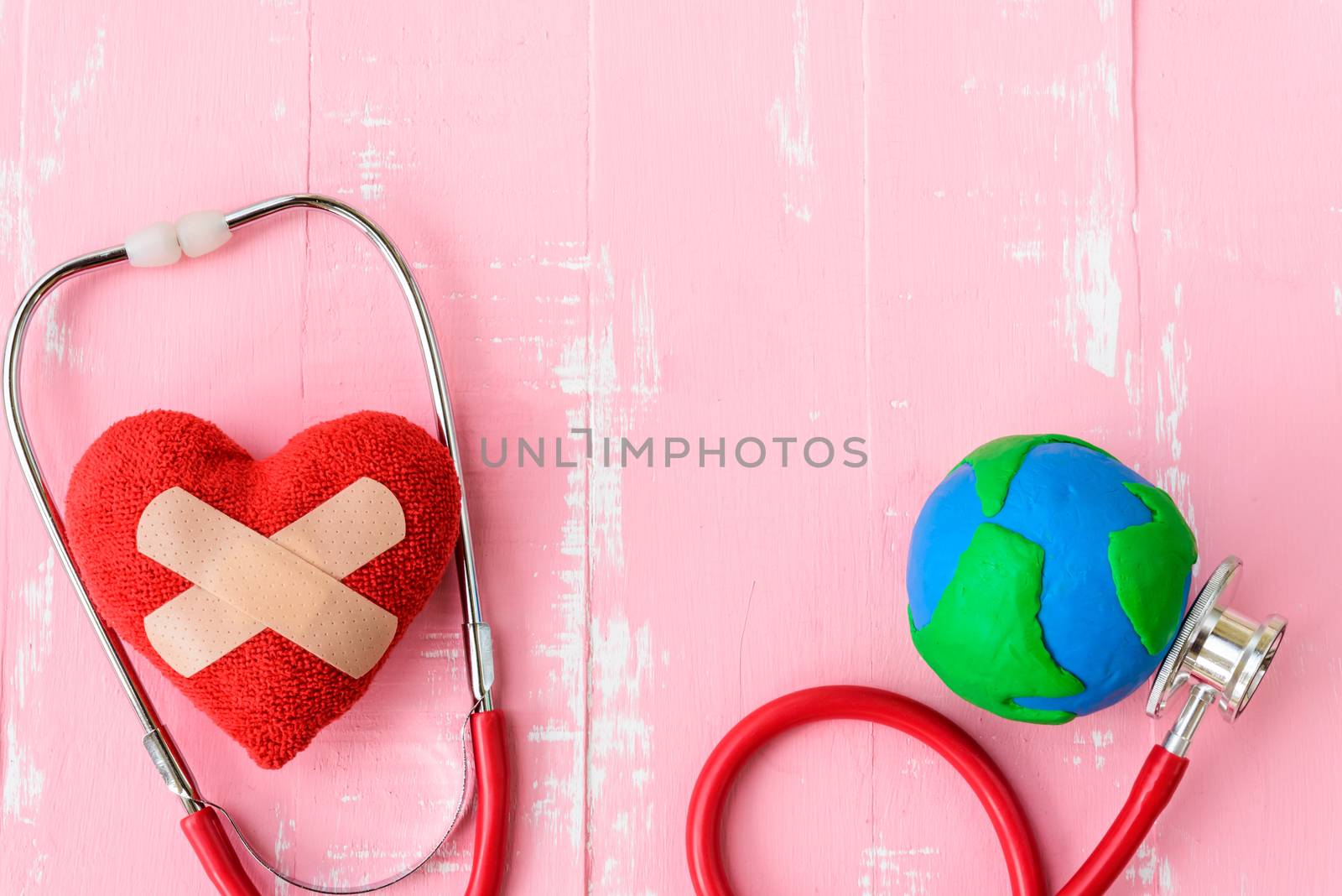 World health day, Healthcare and medical concept. Red heart with Stethoscope, handmade globe, thermometer and yellow Pill on Pastel white and pink wooden background.