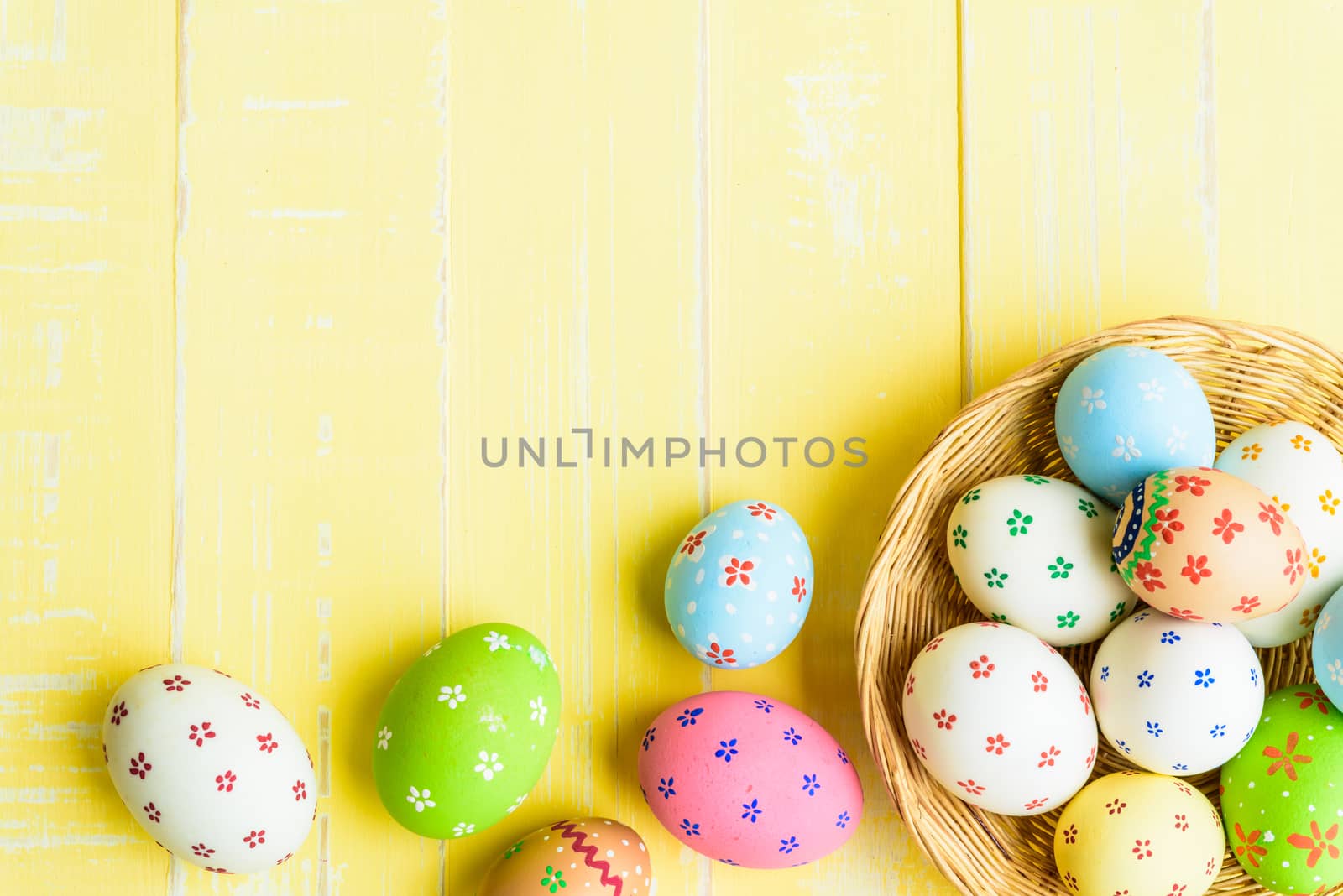 Happy easter! Colorful of Easter eggs in nest with red ribbon, Feather and paper star on pastel color bright yellow and white wooden background.