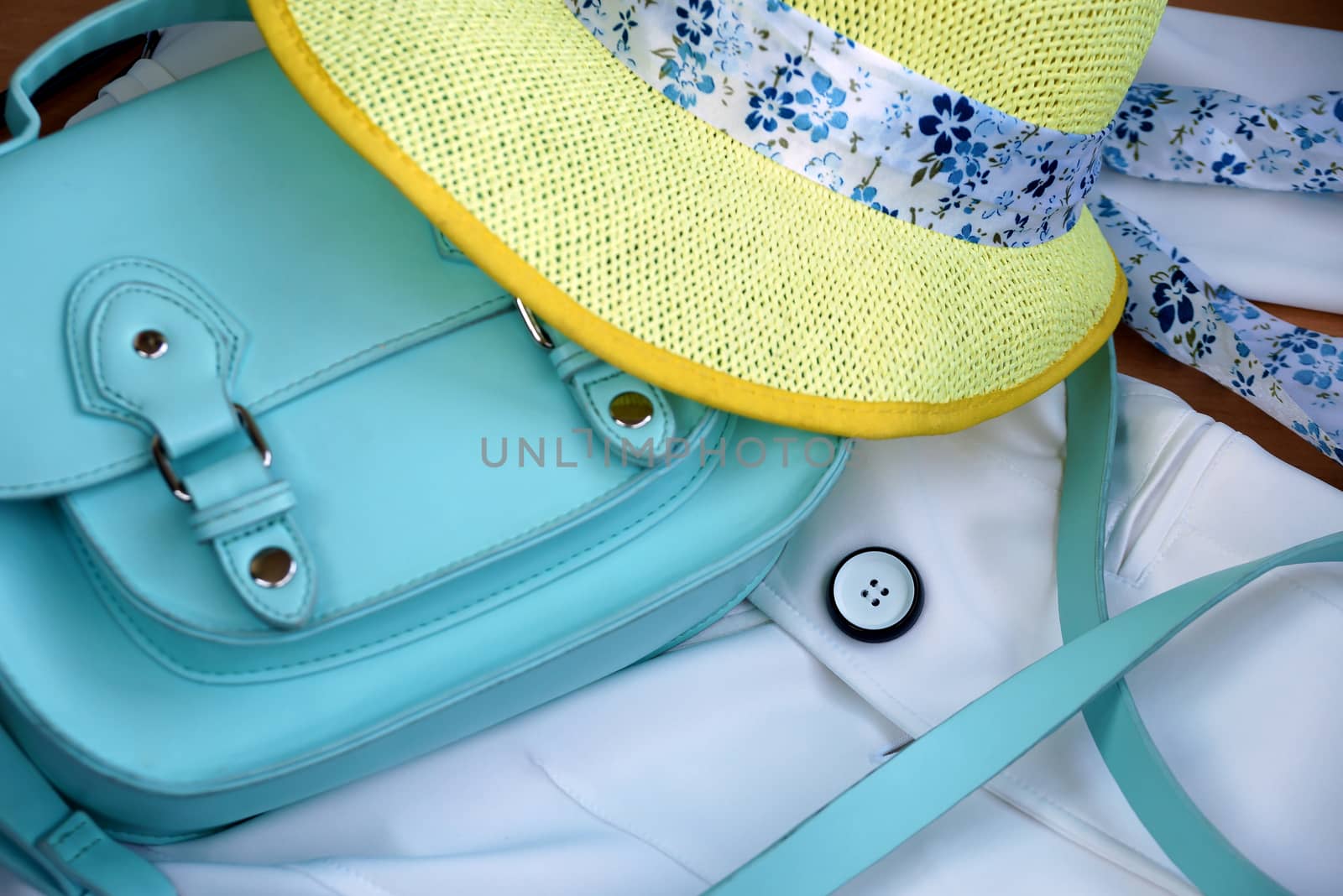 Women turquoise bag and yellow hat on a white jacket