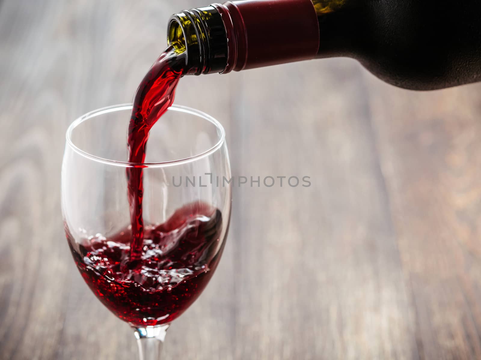 Closeup of red wine pouring in glass. Copy space. Sunflare effect