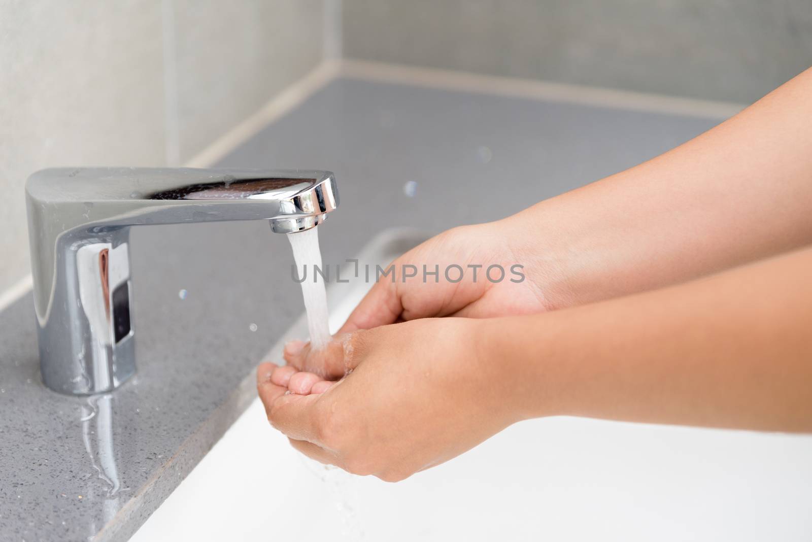 Selective focus of woman washing hands with soap under the faucet with water  in the bathroom.