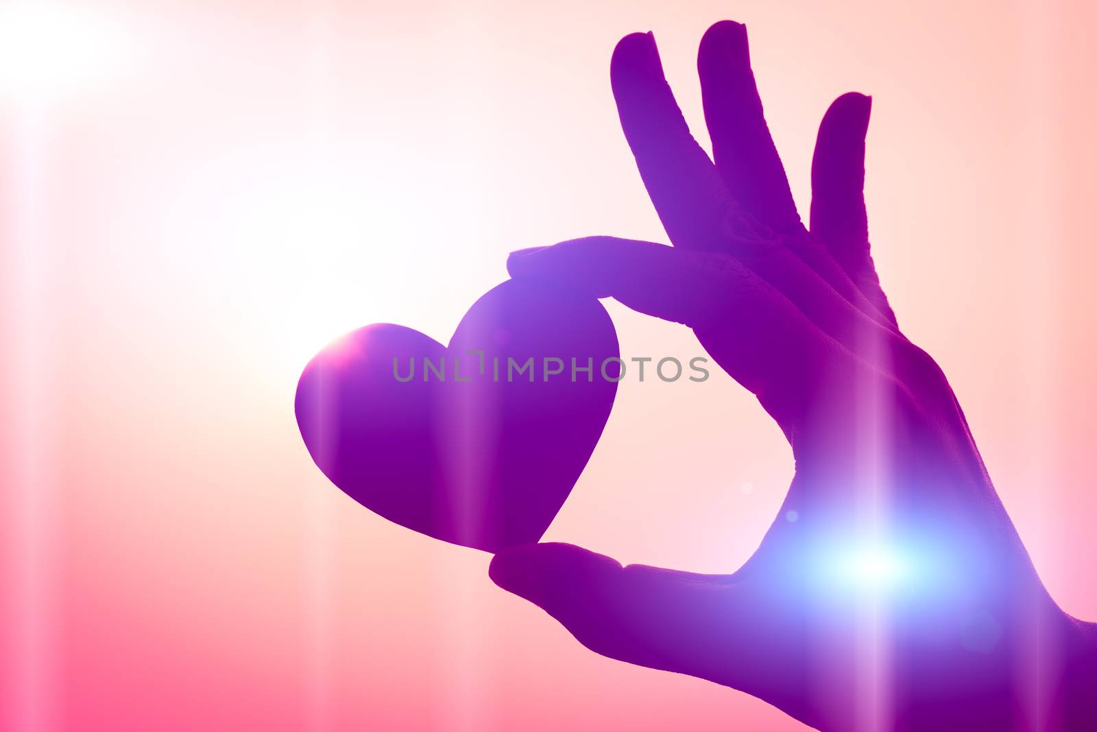 Close up and Silhouette of hand holding red heart during sunset  by spukkato