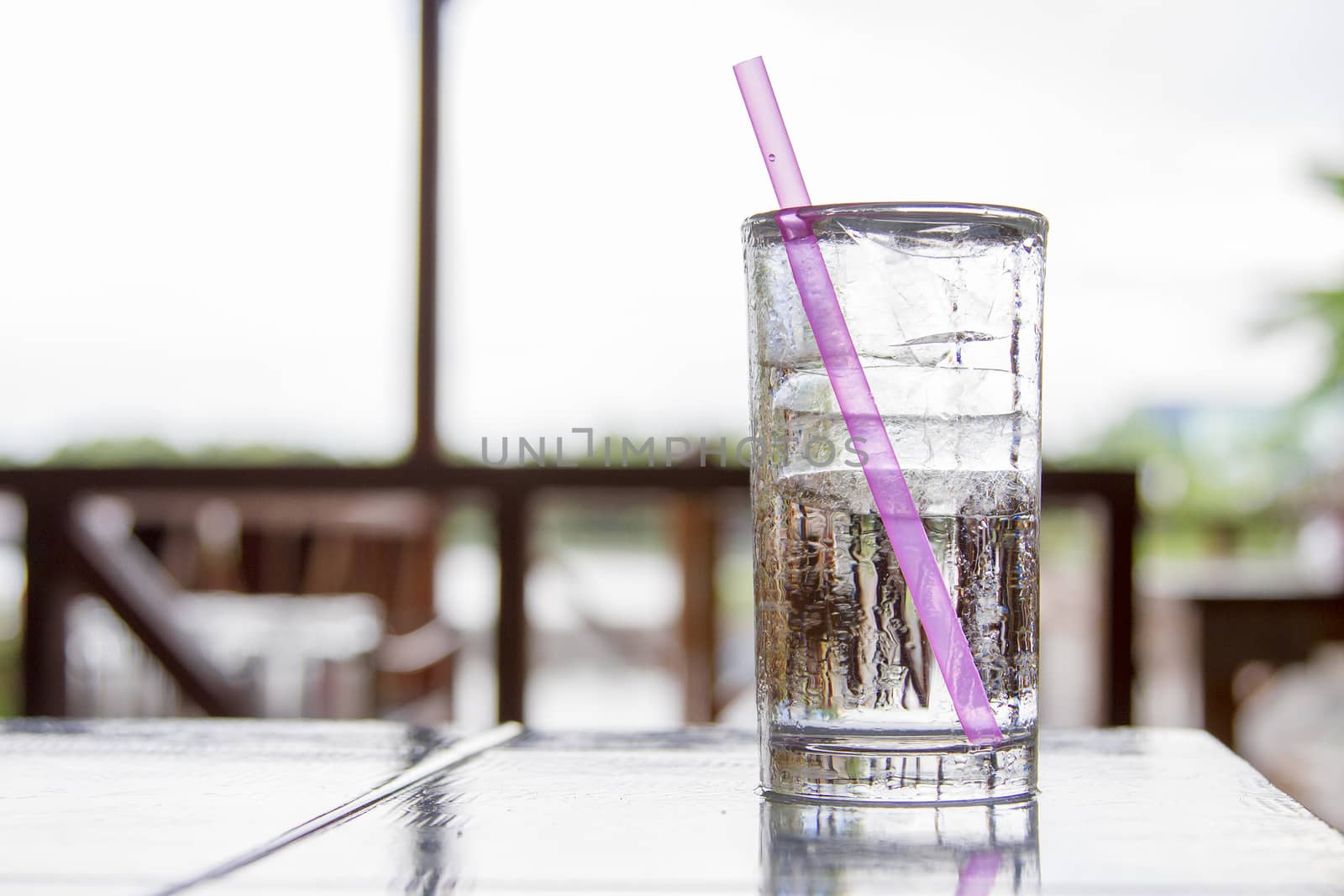 Ice glass placed on a wooden desk. With a pink tube by TakerWalker