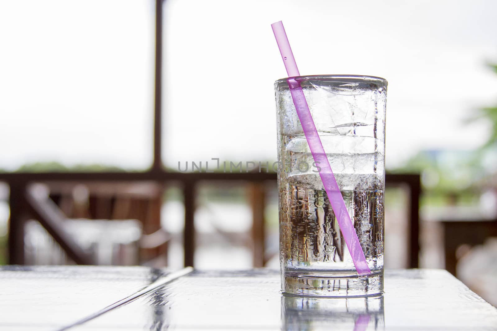 Ice glass placed on a wooden desk. With a pink tube