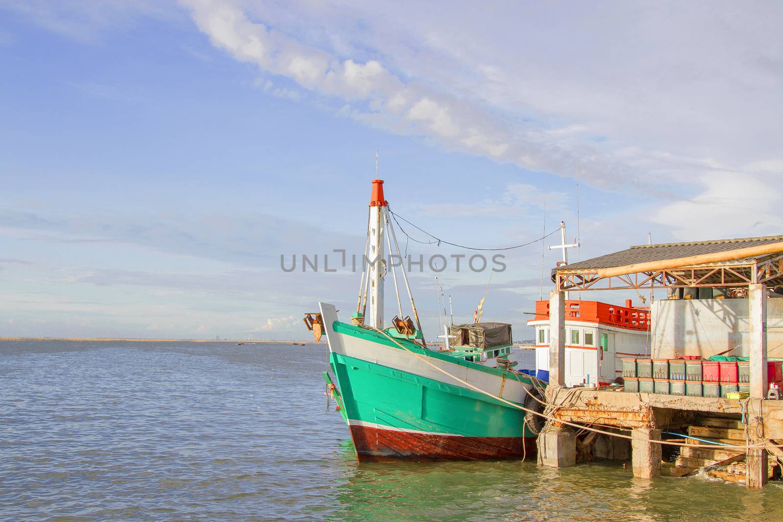 The green fishing boat is whitewashed against the pier with blue by TakerWalker