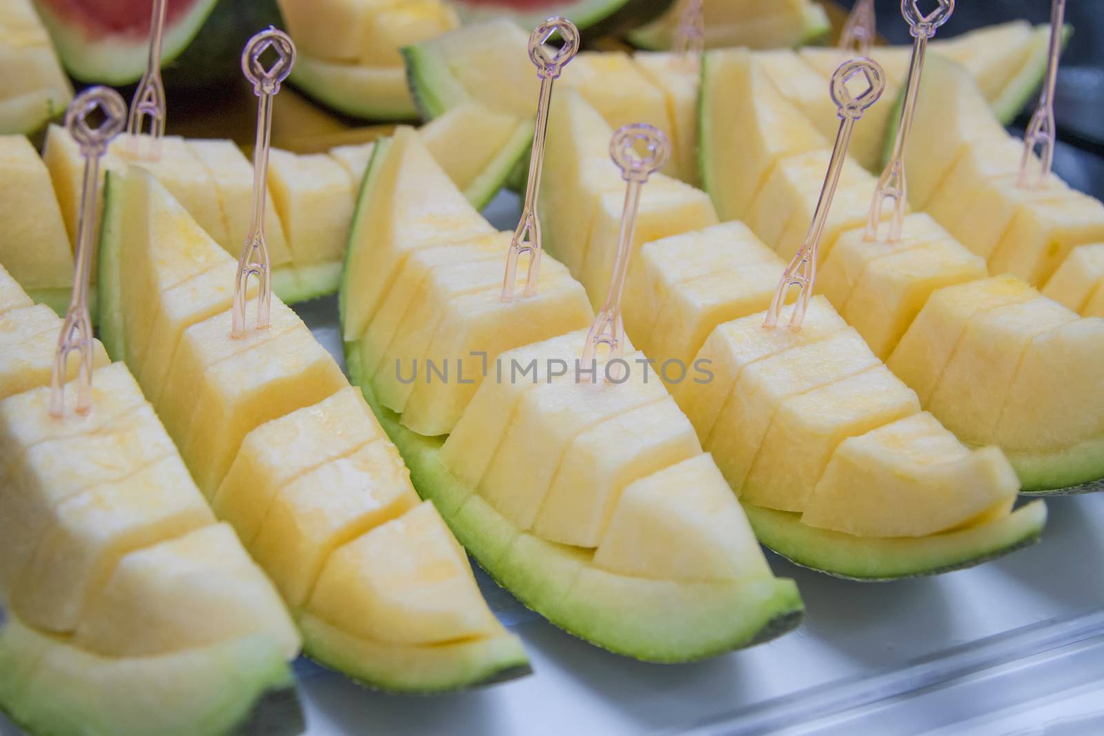 Melon sliced on a tray with a dipper.