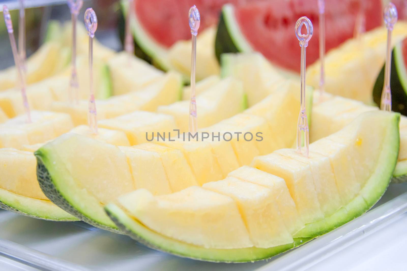 Melon sliced on a tray with a dipper.