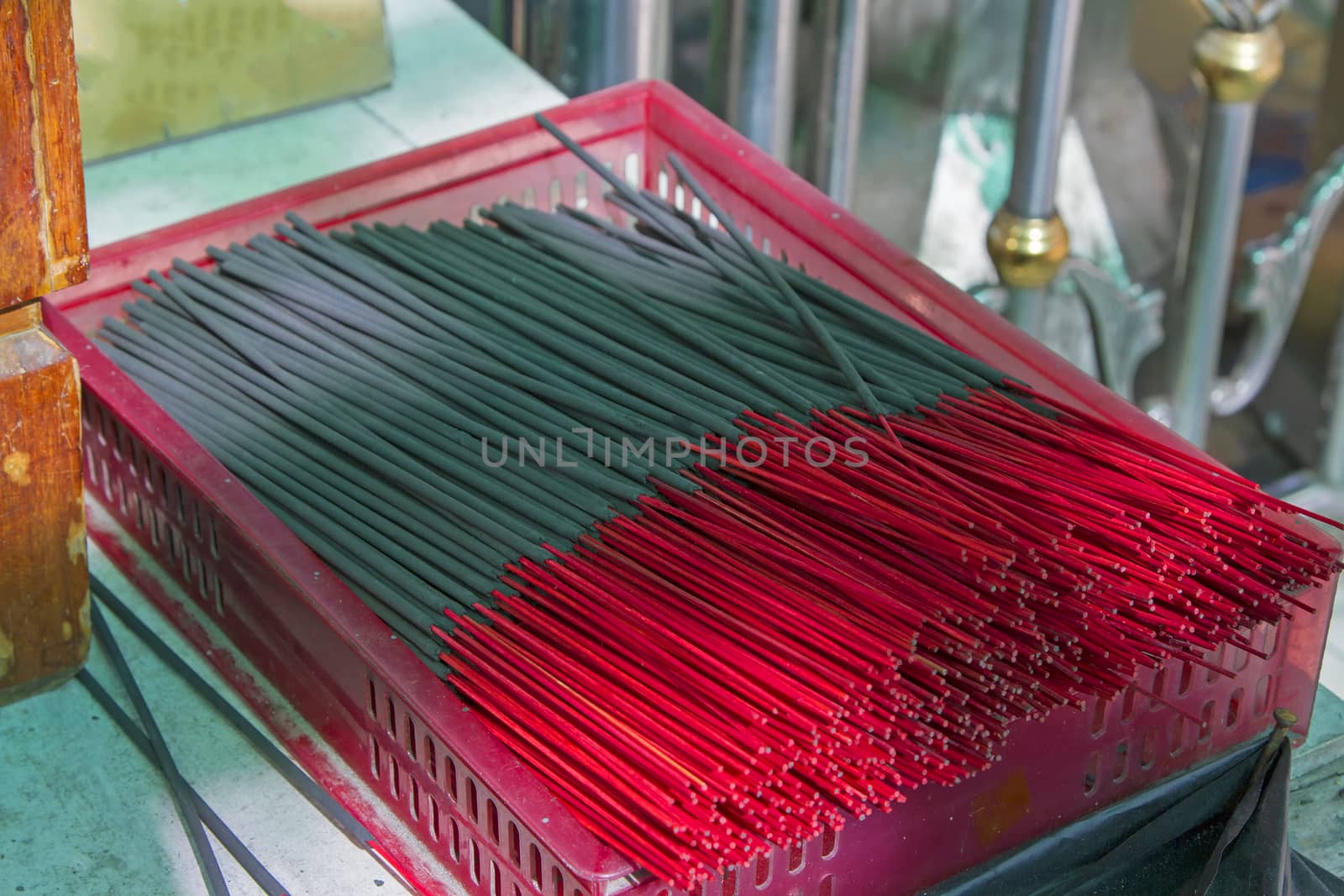 Many black incense sticks in a red basket.