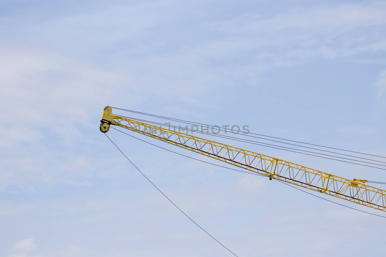 Crane lifts old yellow with blue sky. by TakerWalker