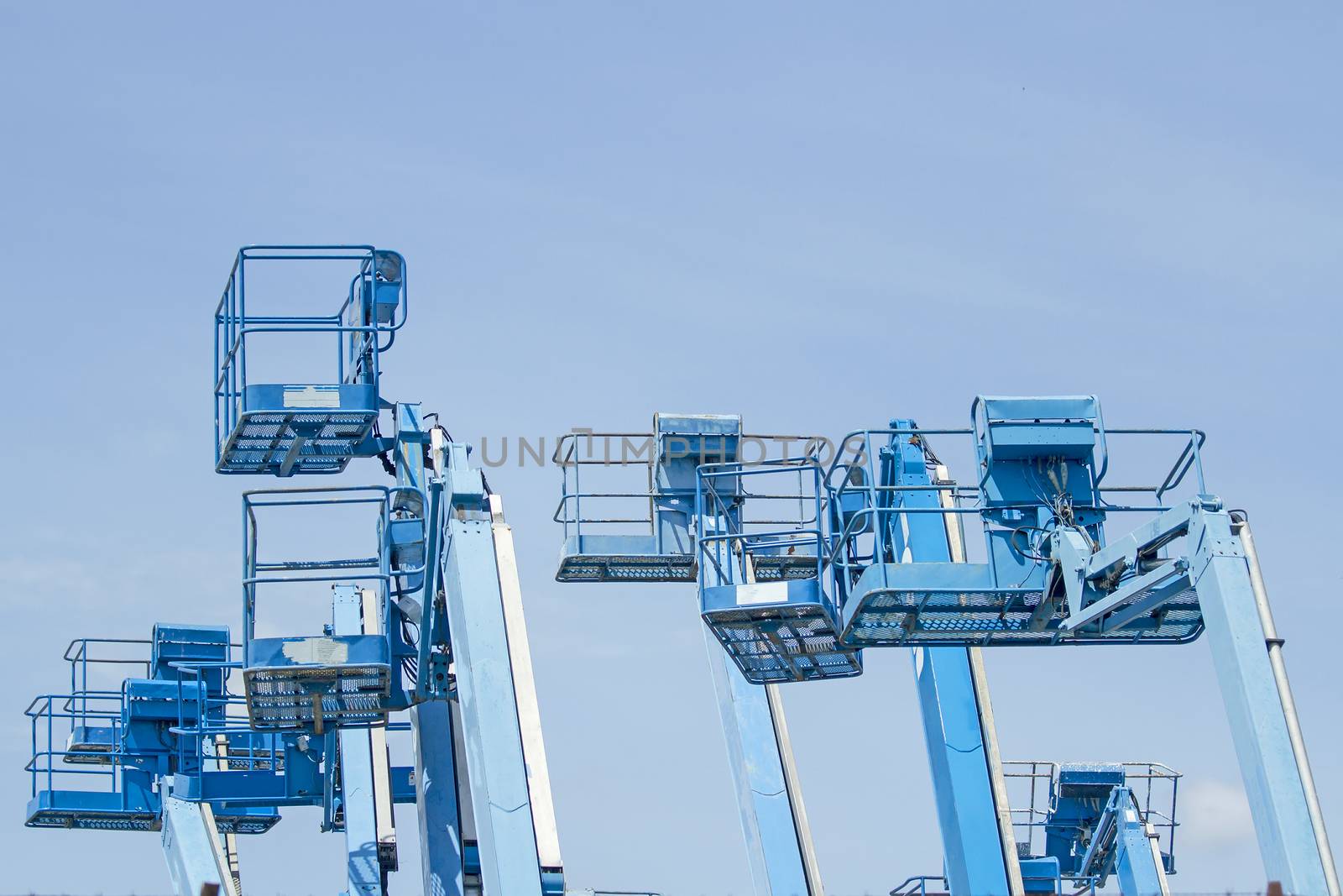 Basket of multiple forklifts are old of blue on blue sky background