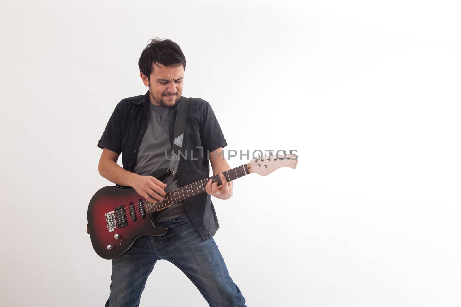 young man jumping with electric guitar on white background