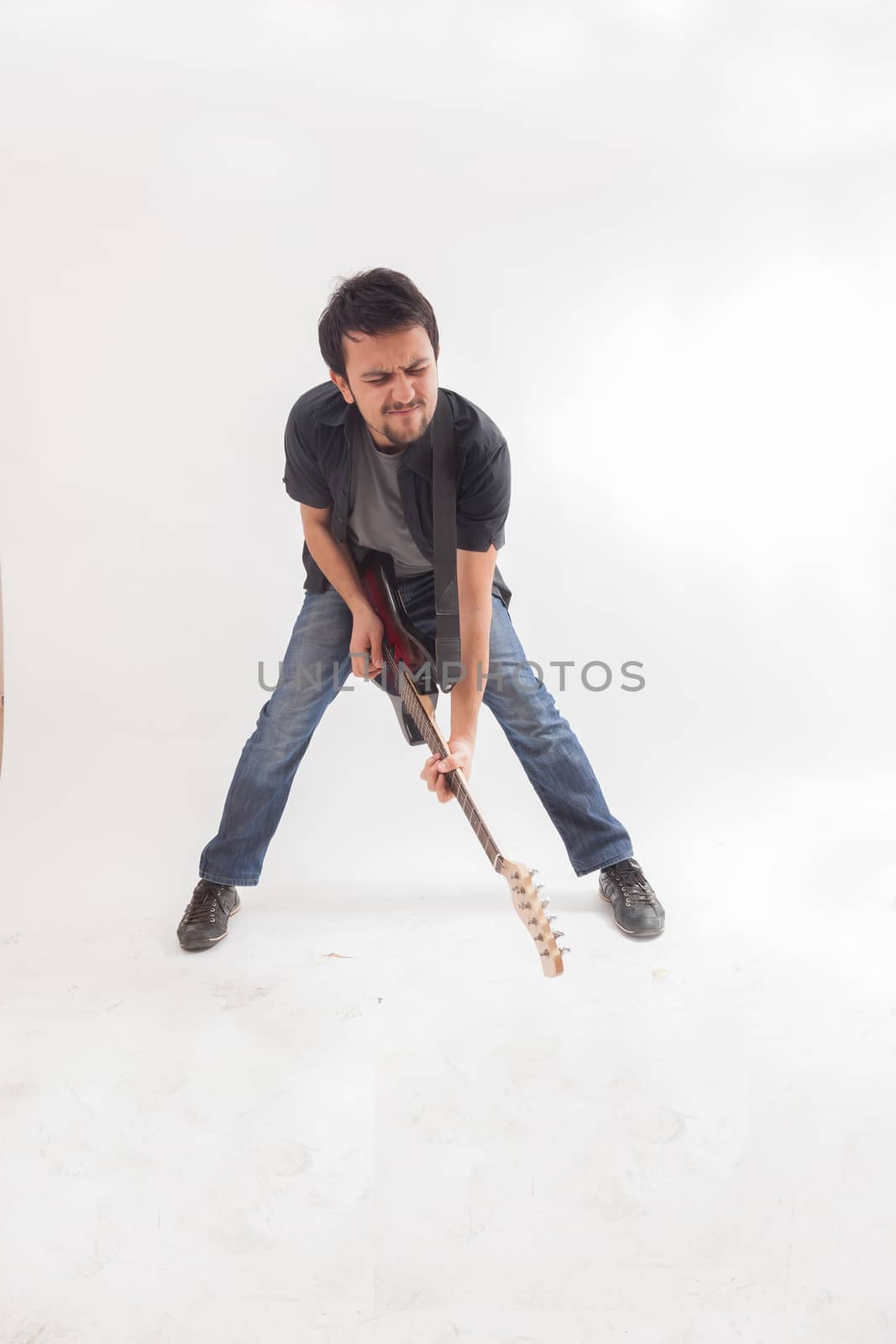 young man jumping with electric guitar on white background