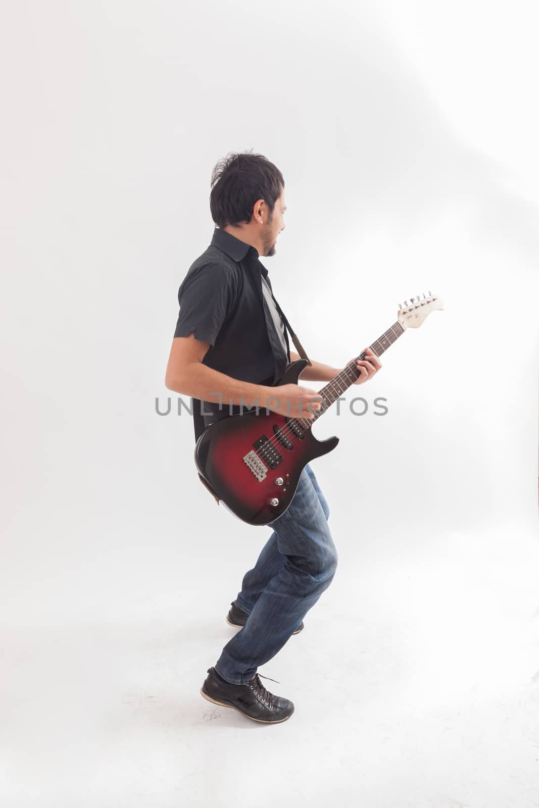 young man jumping with electric guitar on white background