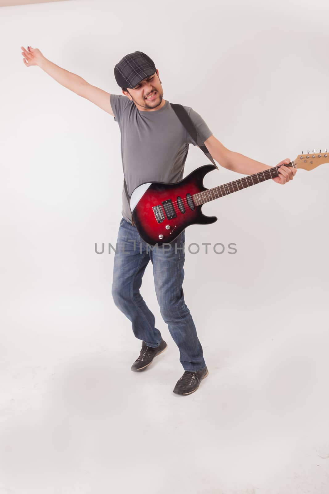 young man jumping with electric guitar on white background