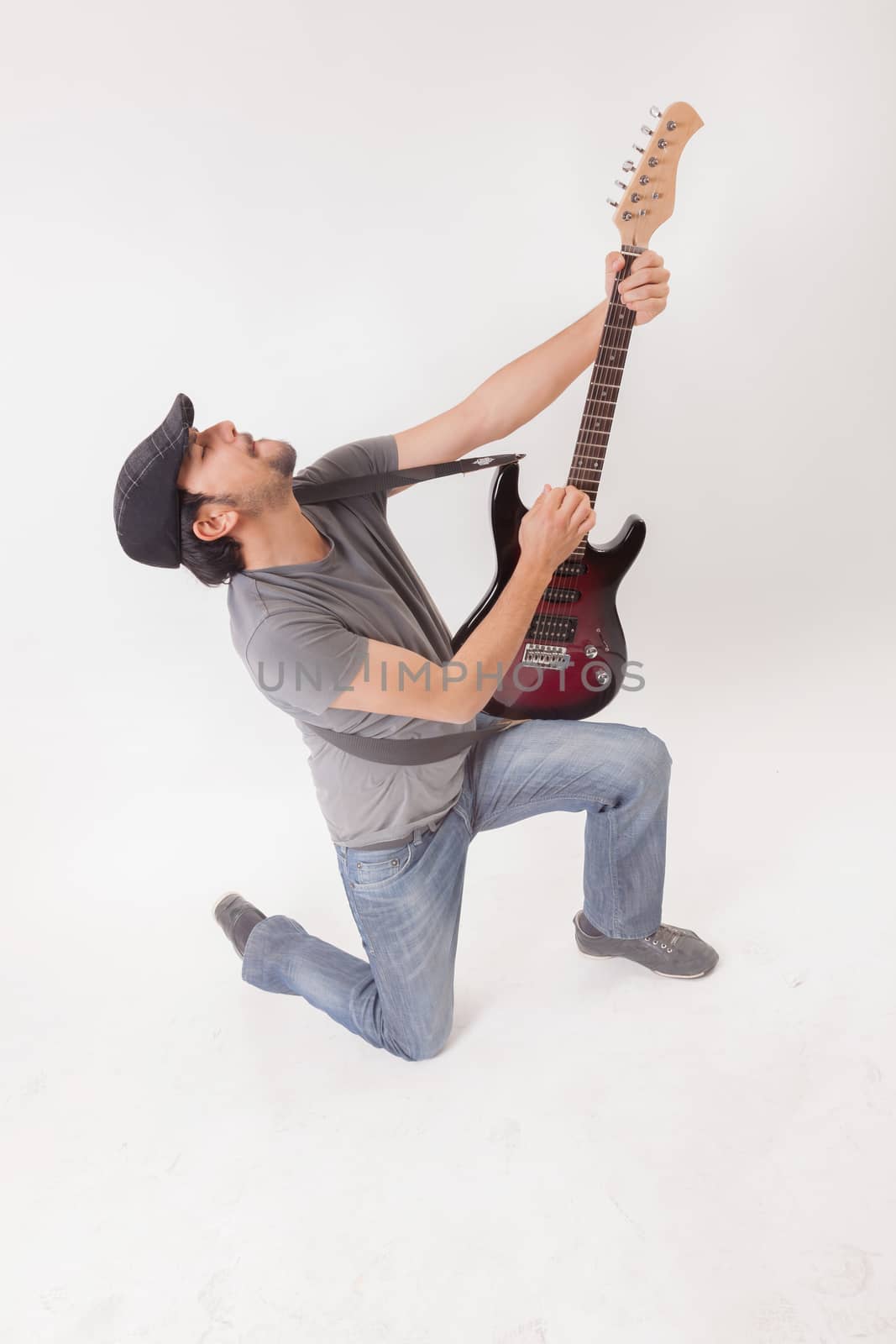 young man jumping with electric guitar on white background