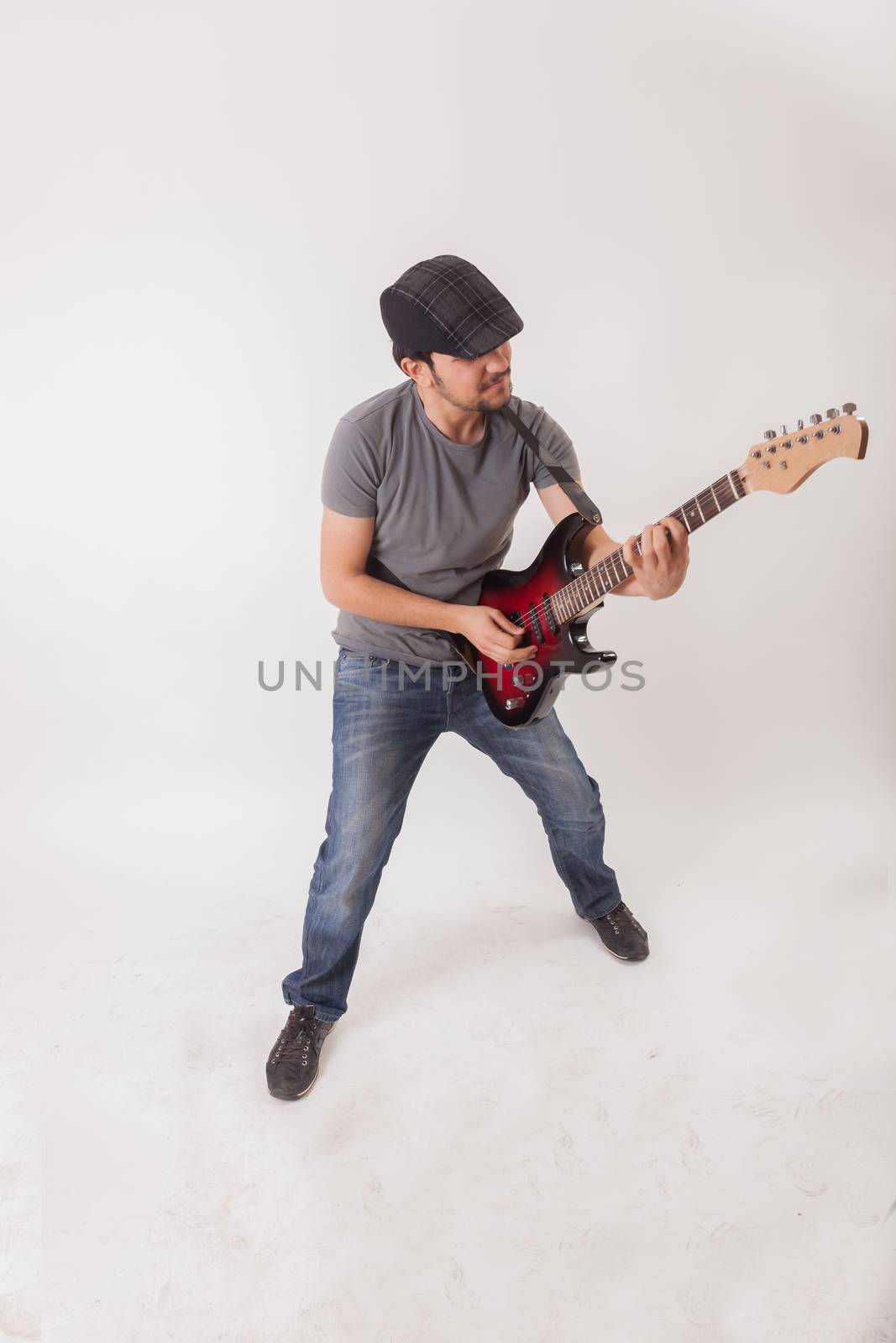 young man jumping with electric guitar on white background