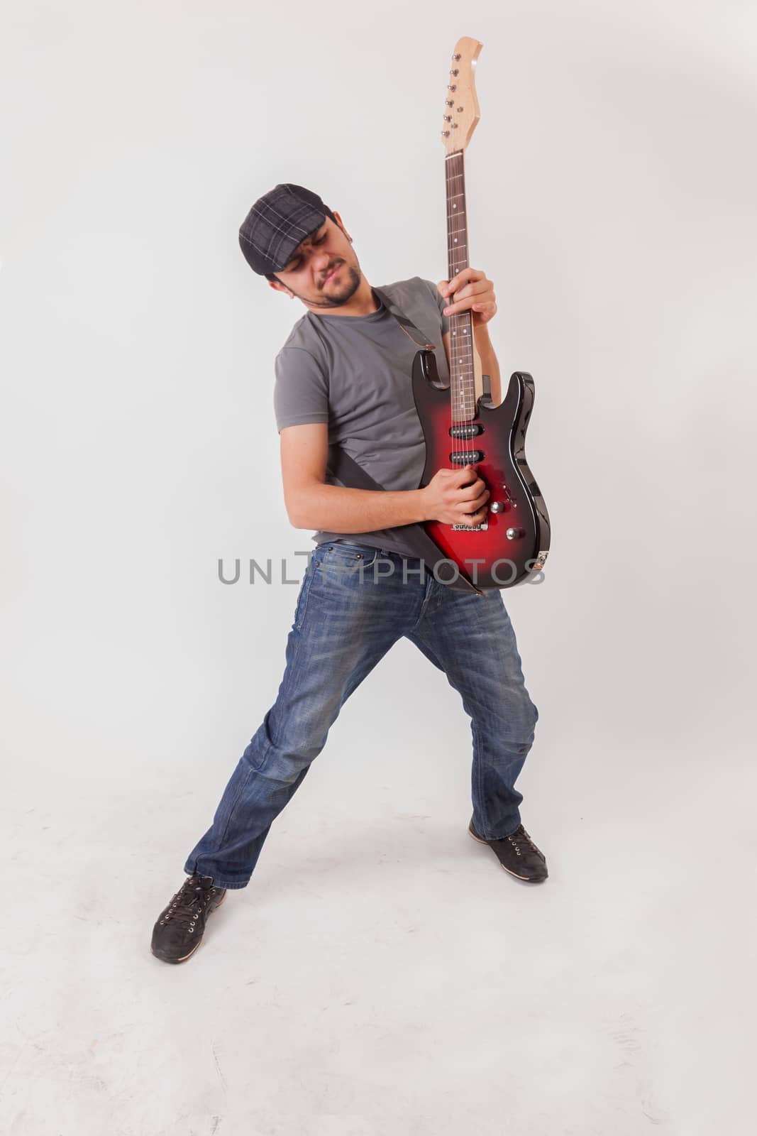 young man jumping with electric guitar on white background