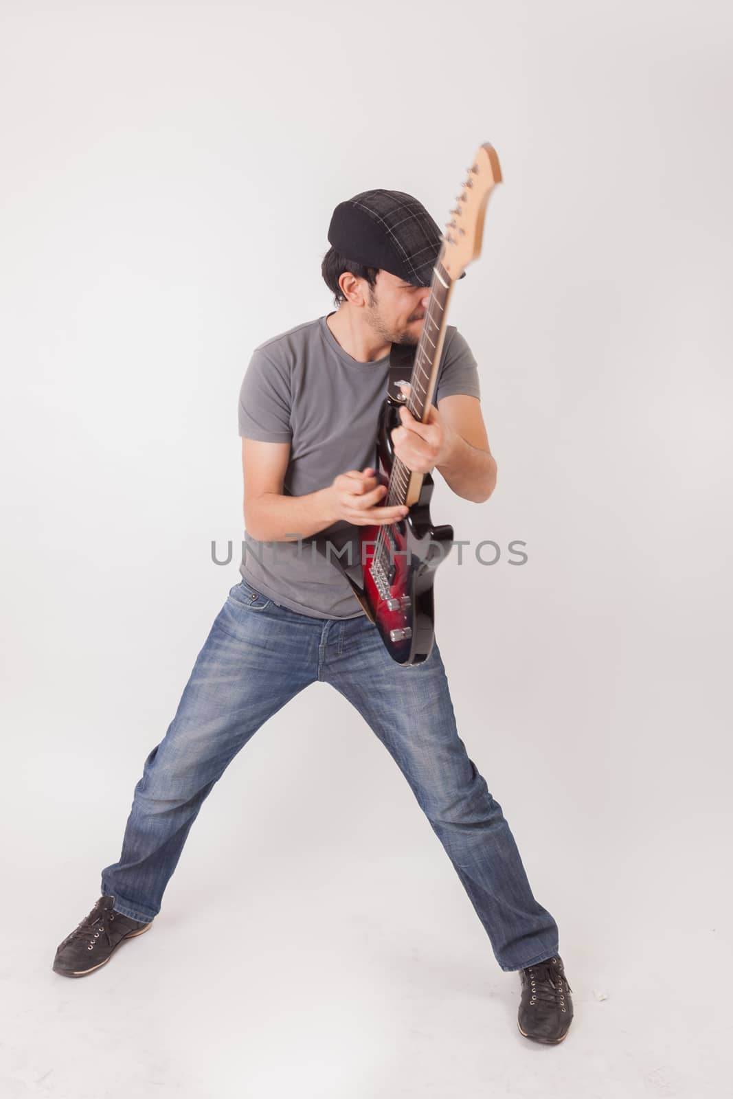 young man jumping with electric guitar on white background