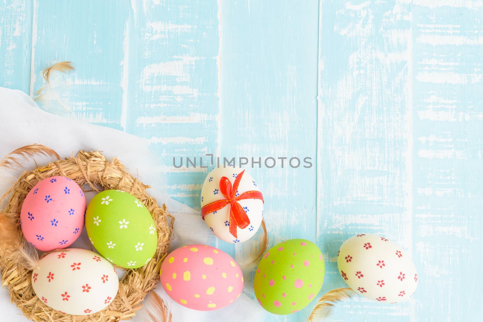 Happy easter! Colorful of Easter eggs in nest on pastel color bright green and white wooden background.