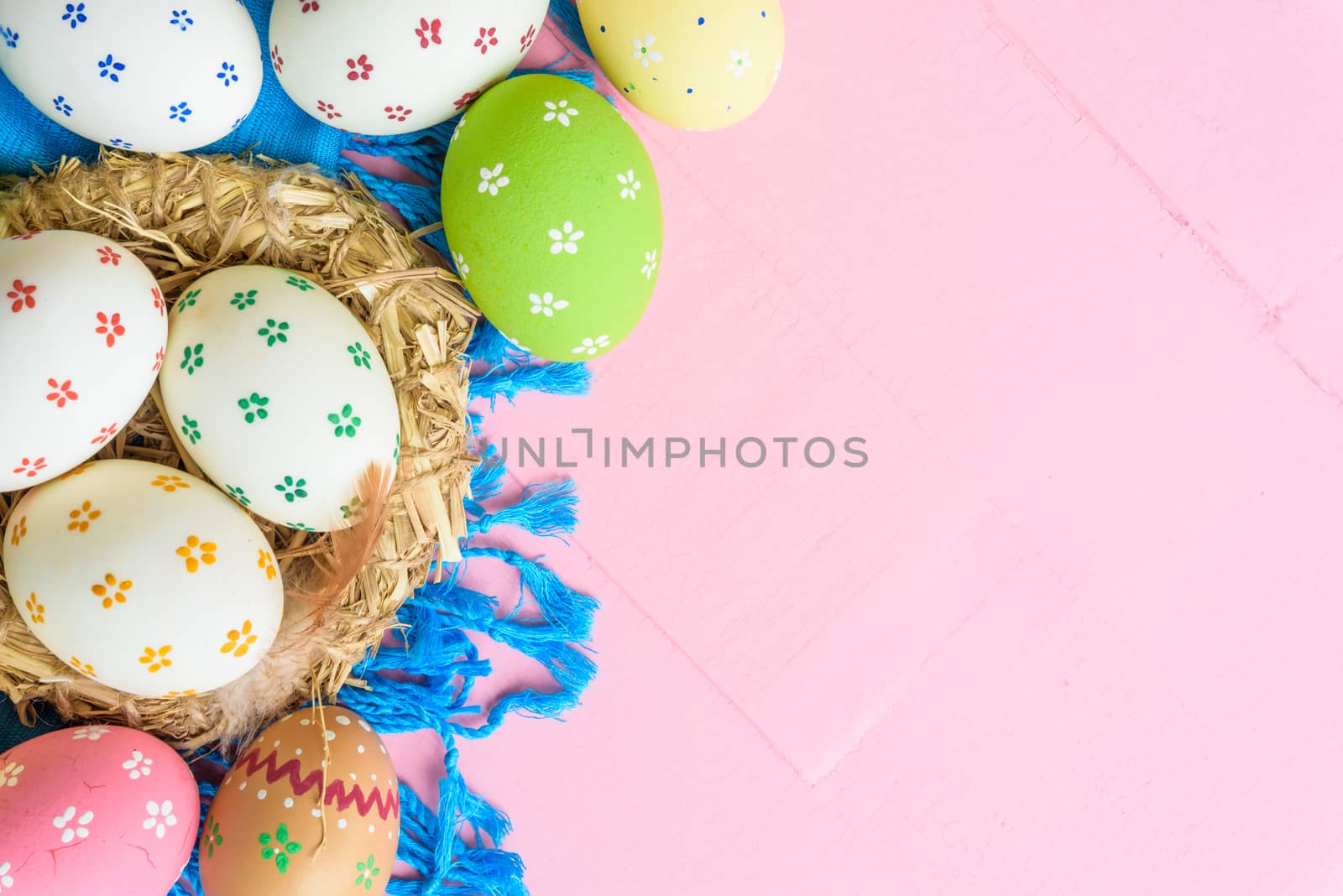 Happy easter! Colorful of Easter eggs in nest with paper star, flower and Feather on pastel color bright pink and white wooden background.