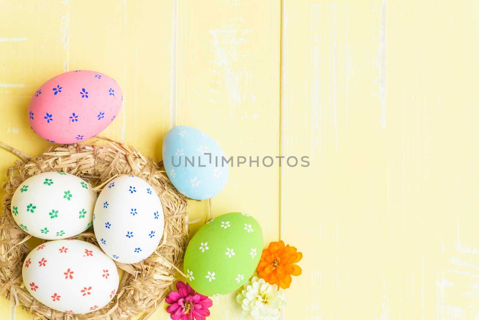 Happy easter! Colorful of Easter eggs in nest with red ribbon, Feather and paper star on pastel color bright yellow and white wooden background.